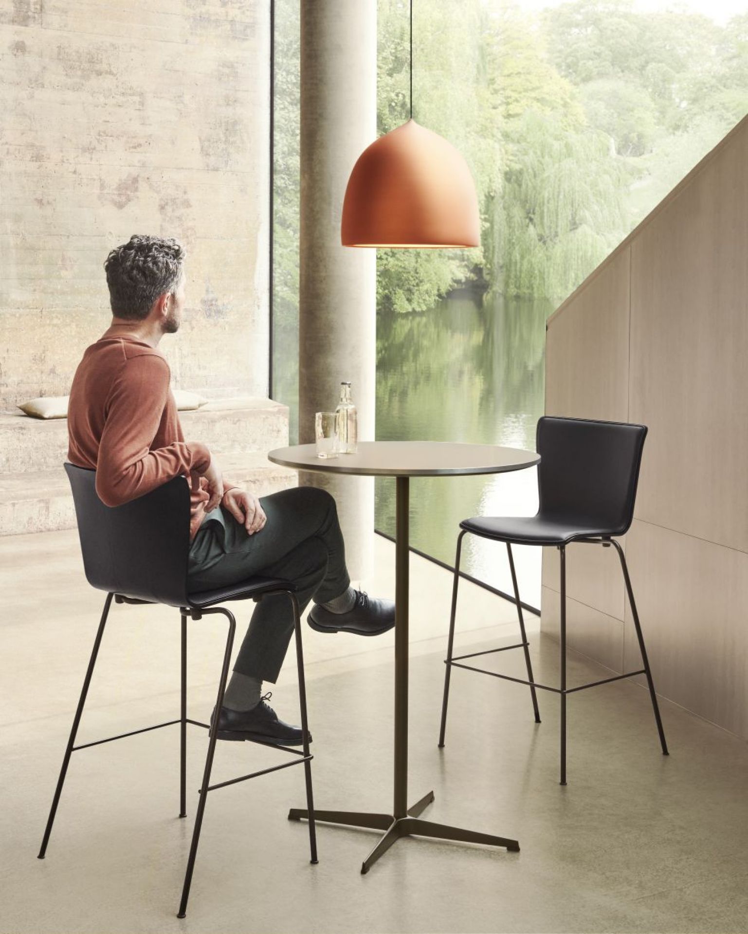 Zirkular Stehtisch von Fritz Hansen mit Person auf Barstuhl in modernem Büro mit Blick auf den See.