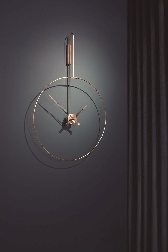 Daro Clock Wanduhr: Moderne Wanduhr mit goldenem Rahmen und Holzdetail vor dunklem Hintergrund.
