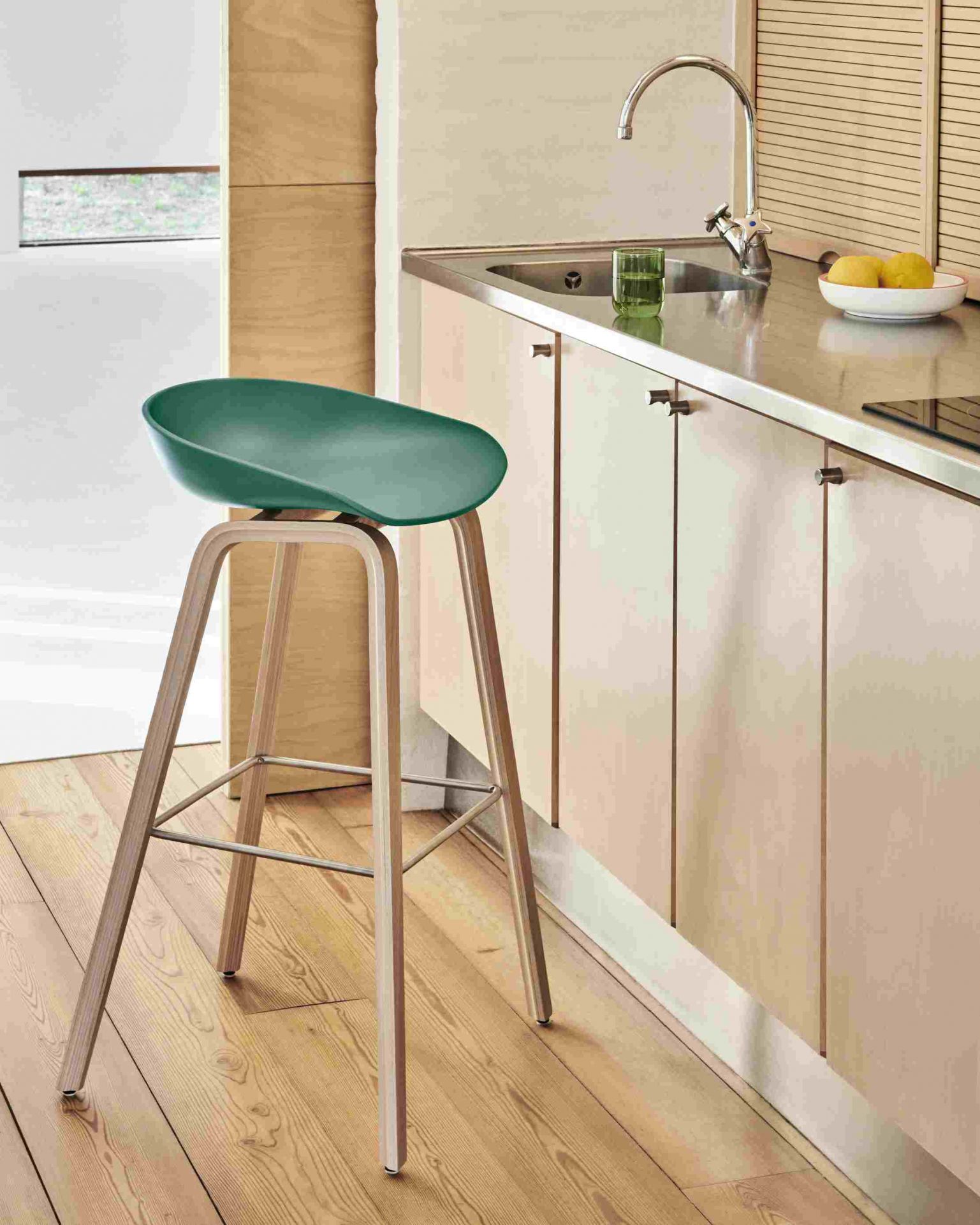 Grüner Hay About a Stool AAS32 Barhocker mit Holzbeinen in einer modernen Küche.