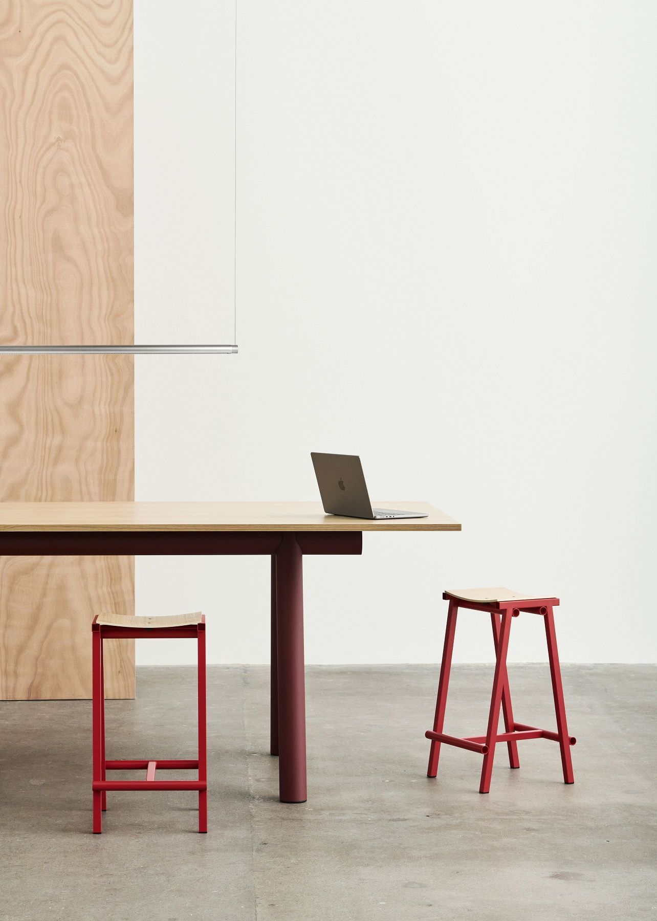 Hay Boa Table Holztisch mit roten Beinen und zwei passenden Hockern im minimalistischen Design.