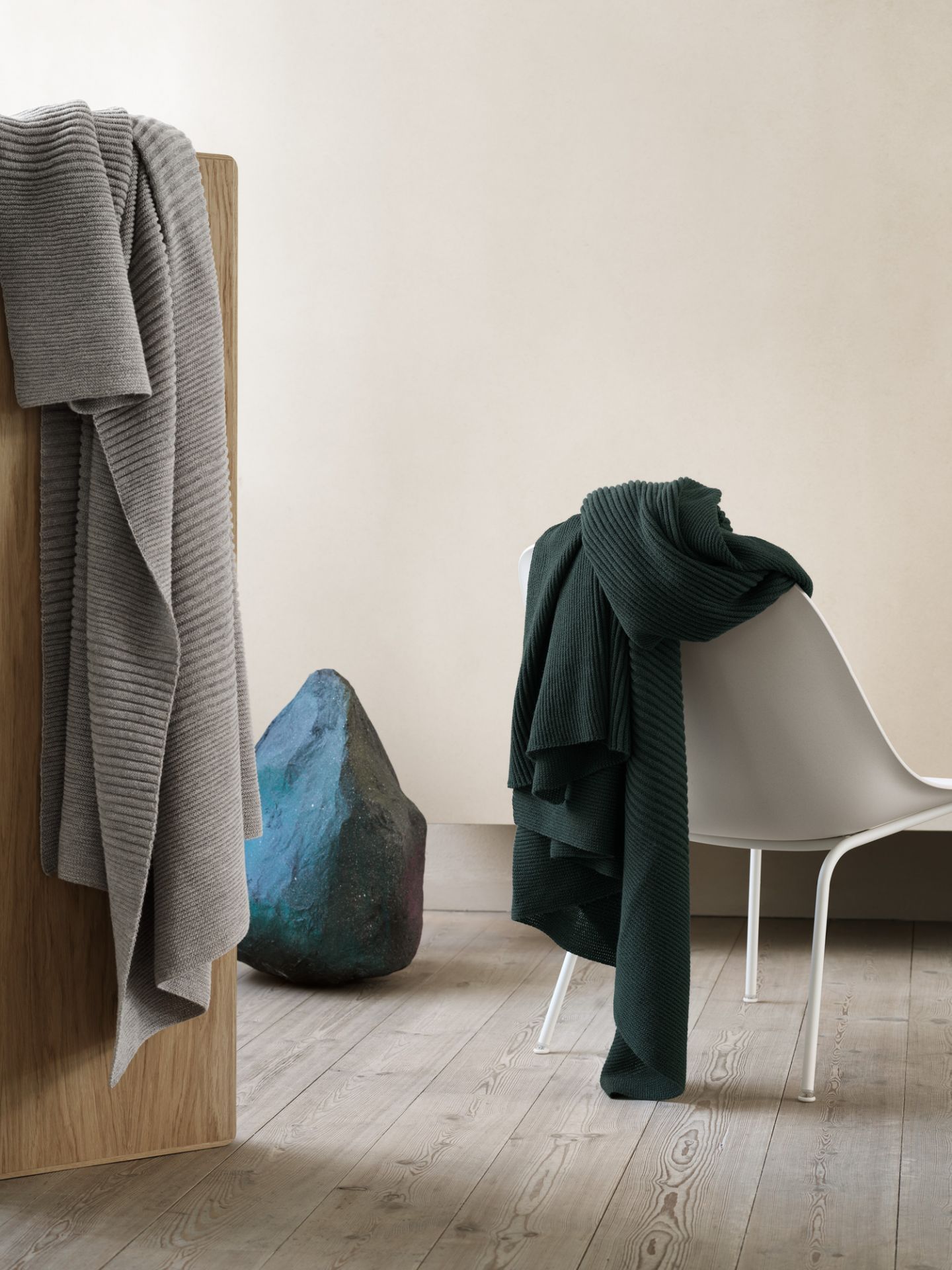 Muuto Fiber Lounge Chair mit Kufengestell, weiß, mit dunkelgrüner Strickdecke, minimalistisches Design.