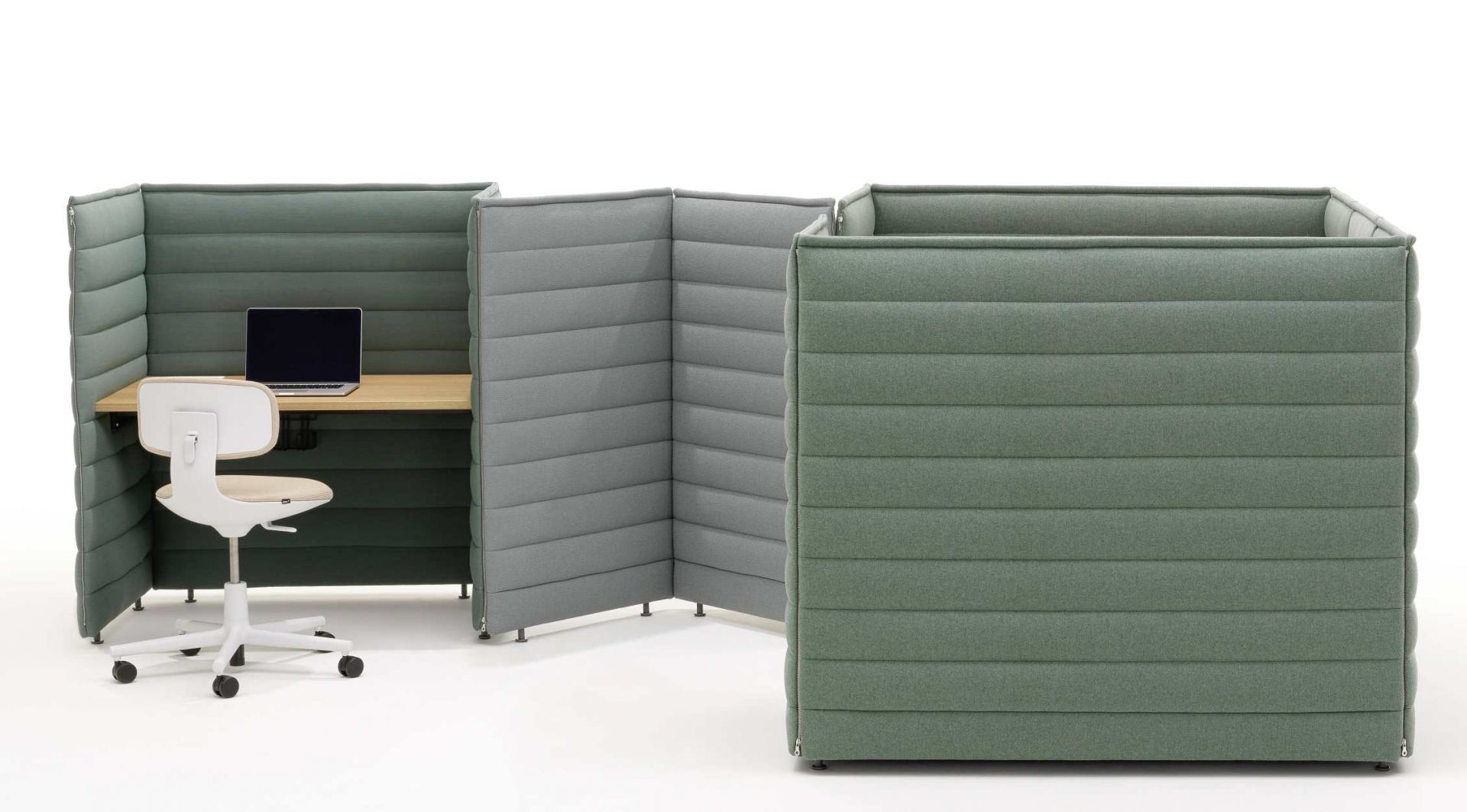 Vitra Alcove Plus Desk Small Schreibtisch mit grünen Akustikwänden, Holztischplatte, Bürostuhl und Laptop.
