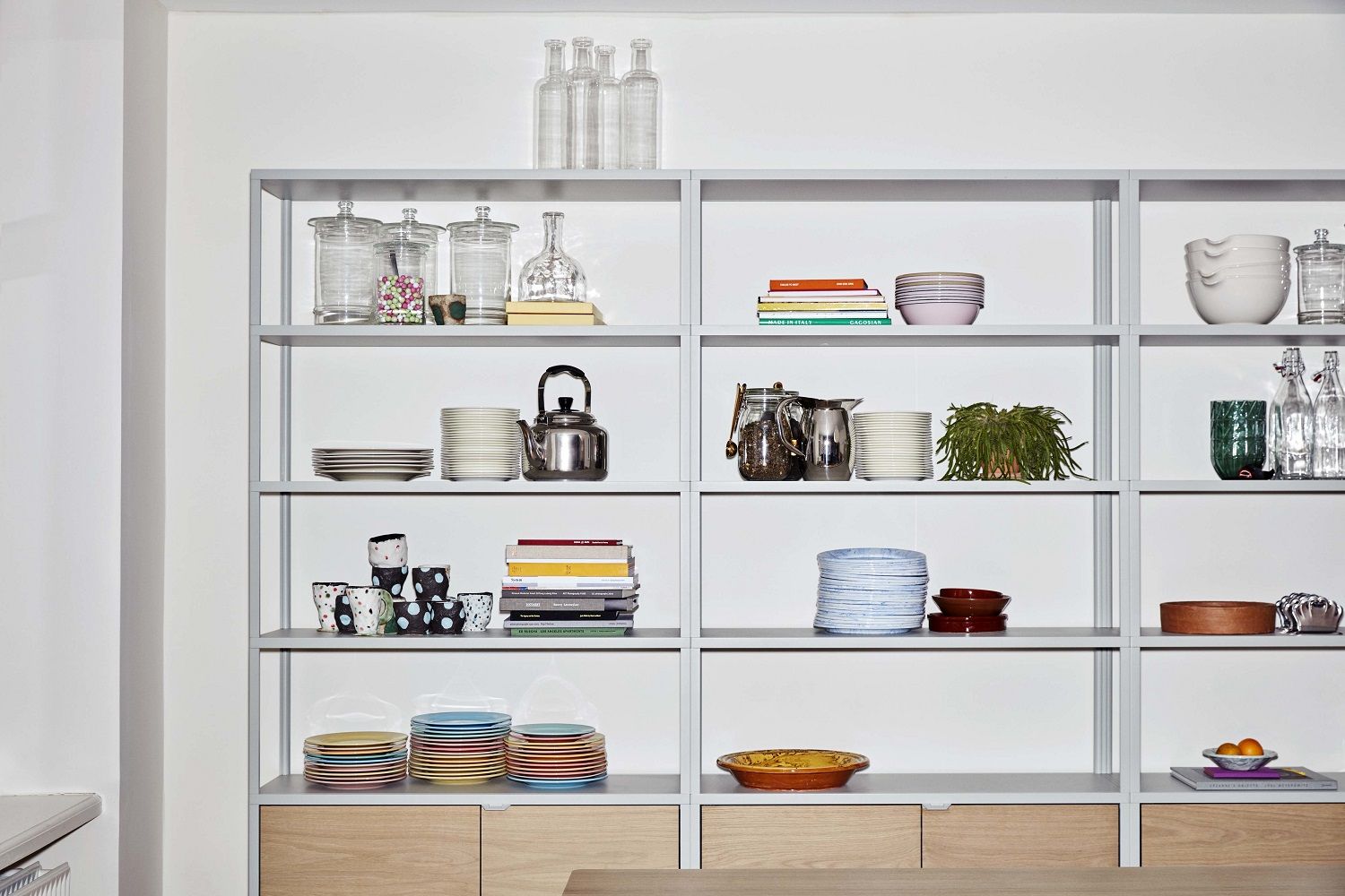 New Order Sideboard von Hay, eine moderne Wandkombination mit Regalen und Holzschränken, gefüllt mit Geschirr.