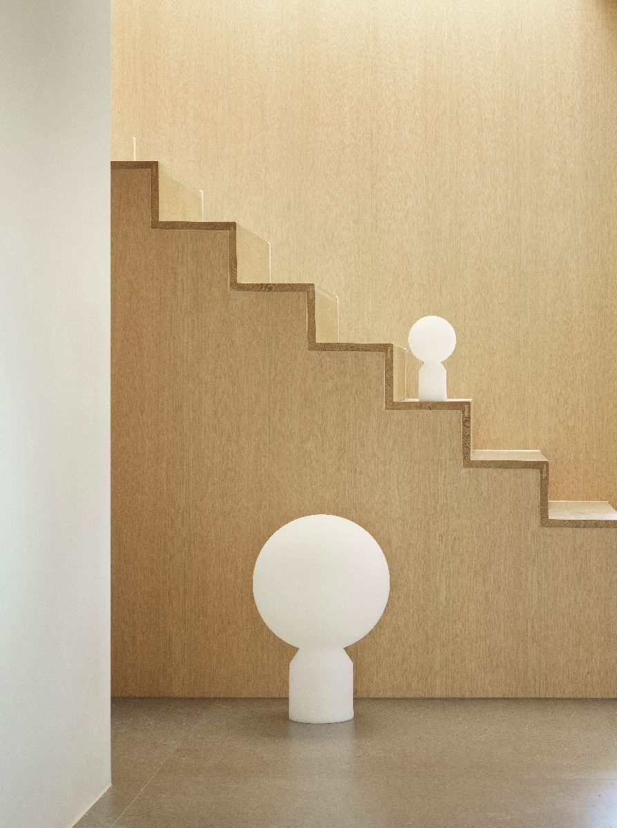Zwei Yo Lamp Tischleuchten von Normann Copenhagen vor einer Treppe und einer hellbraunen Wand.