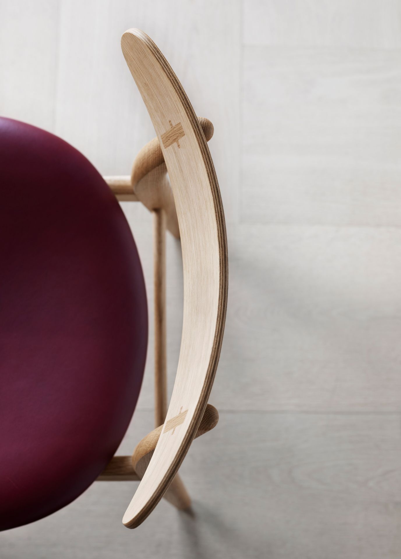 Detailaufnahme des CH30P Chair Stuhls von Carl Hansen & Søn mit bordeauxroter Polsterung und hellem Holzrahmen.