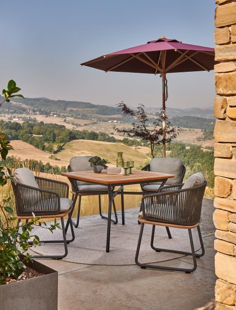 Weishäupl Sonnenschirm Klassiker über einem Gartentisch mit Stühlen, im Hintergrund eine malerische Landschaft.