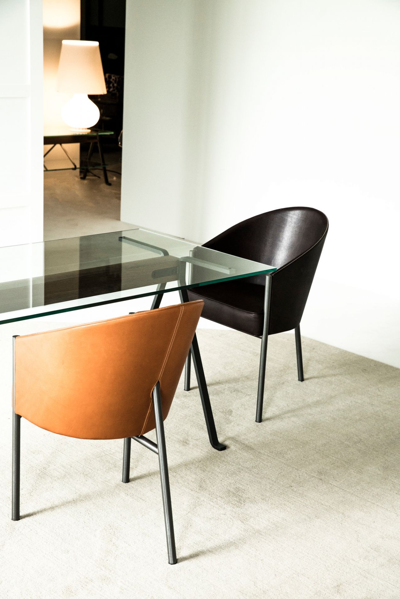 Costes Armchair von Driade: Leder Armlehnstuhl in Braun und Orange am Glastisch.
