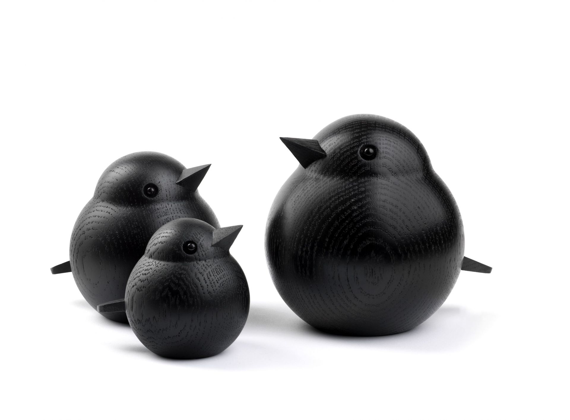 Drei schwarze Holzfiguren, die eine Vogelfamilie darstellen: Papa Sparrow, Mama und Baby.