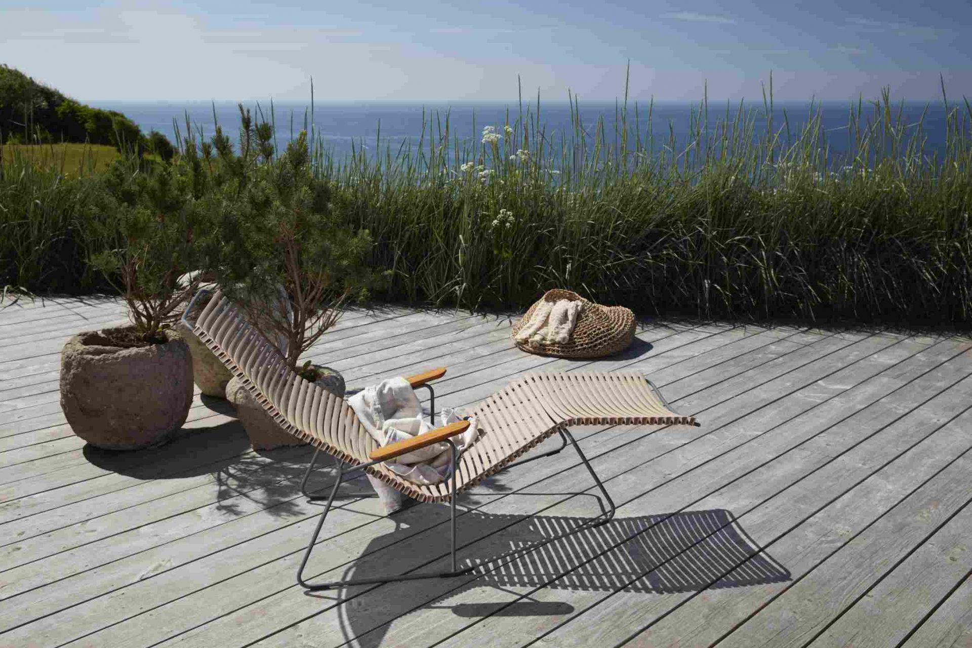 Click Sunlounger Sonnenliege von Houe auf Holzterrasse mit Meerblick, ideal für entspannte Stunden im Freien.