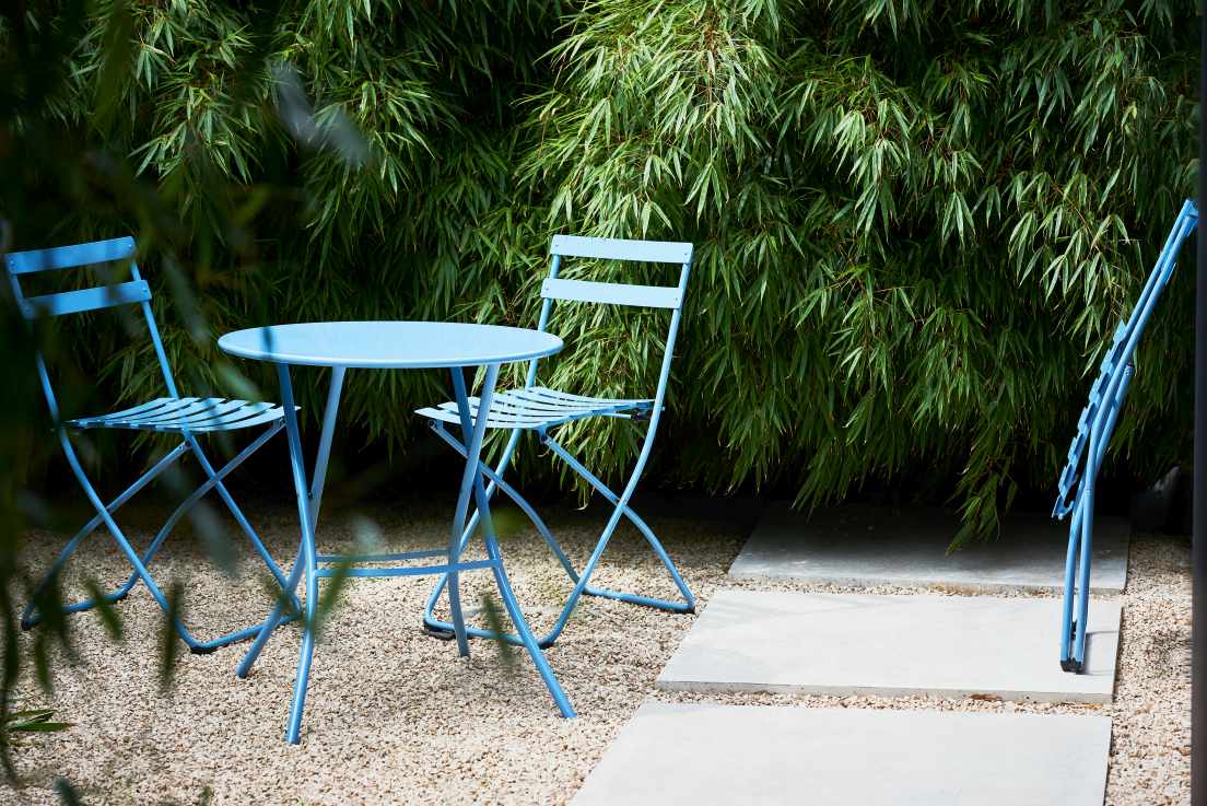 Blauer Fiam Sirio Klapptisch Ø 67 cm von Jan Kurtz mit zwei Stühlen im Garten.