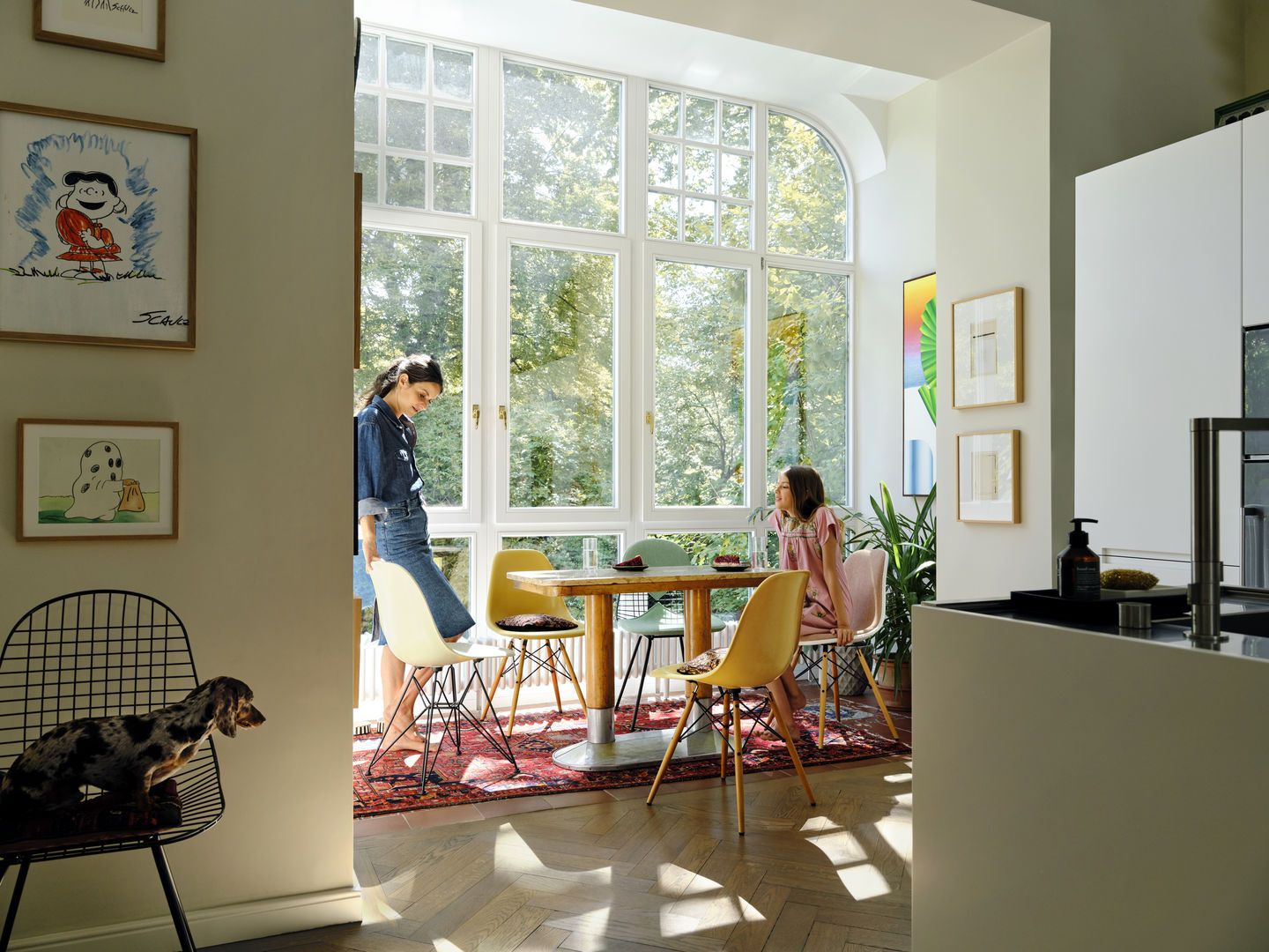 Helle Küche mit Esstisch und bunten Eames Plastic Side Chairs DSW Stühlen von Vitra, zwei Frauen.