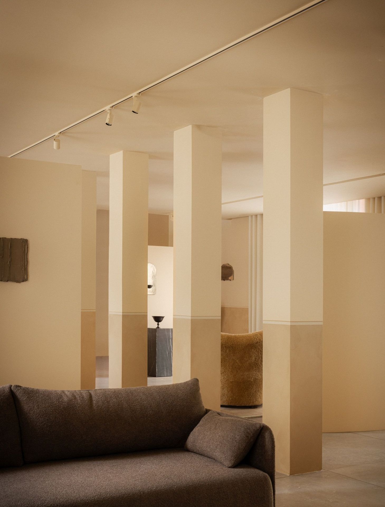 Nahaufnahme des braunen Audo Copenhagen Offset Sofas mit drei Sitzen in minimalistischem, beigem Interieur.