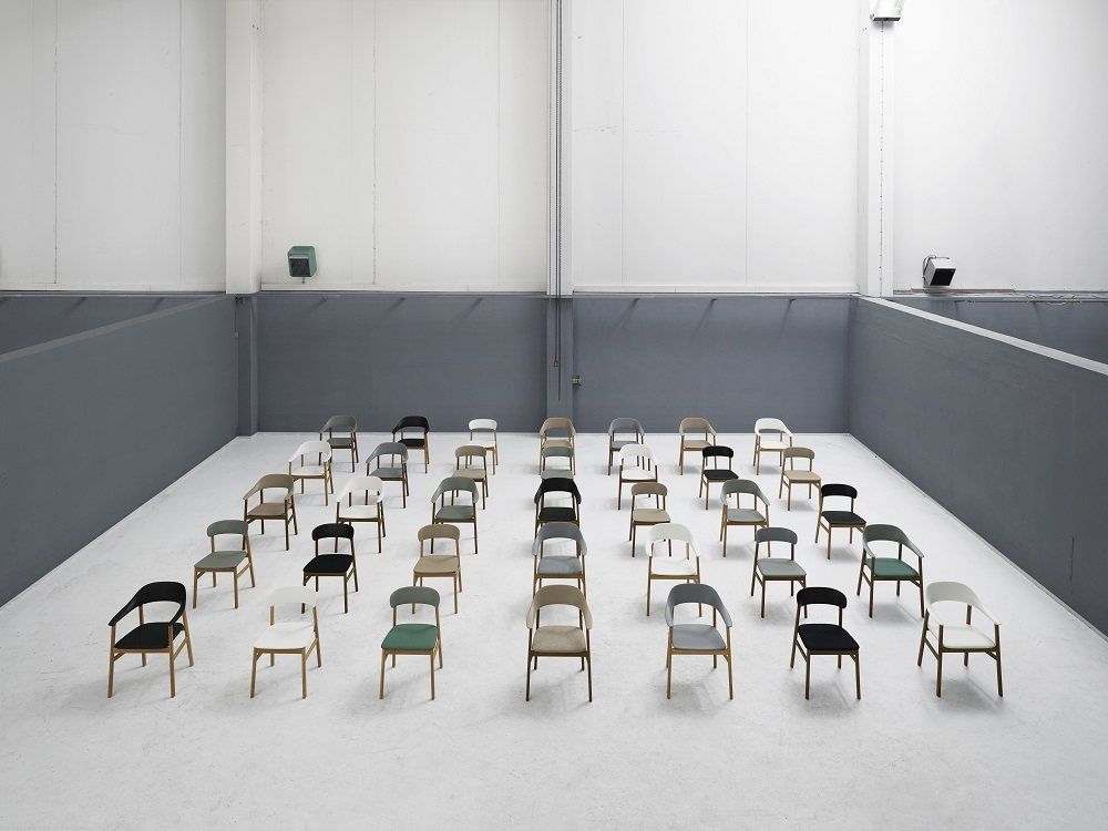 Viele Herit Stühle von Normann Copenhagen in verschiedenen Farben in einem minimalistischen Raum.