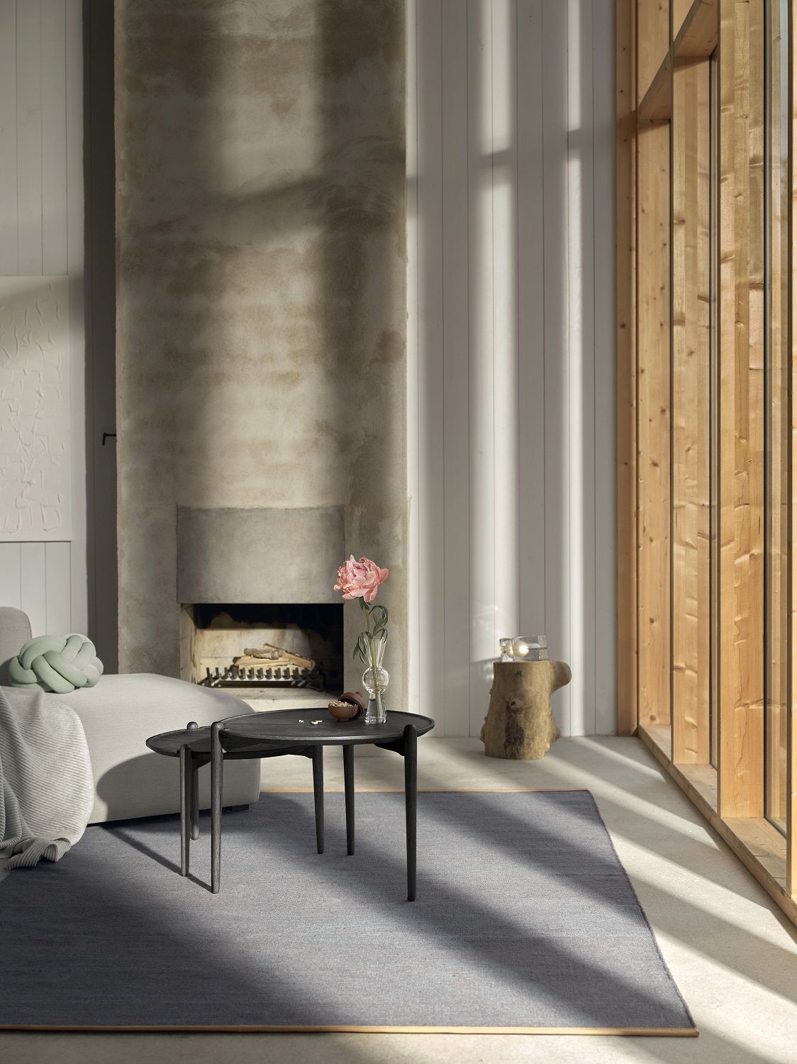 Aria Table Beistelltisch von Design House Stockholm im Wohnzimmer mit Kamin und Holzwand.