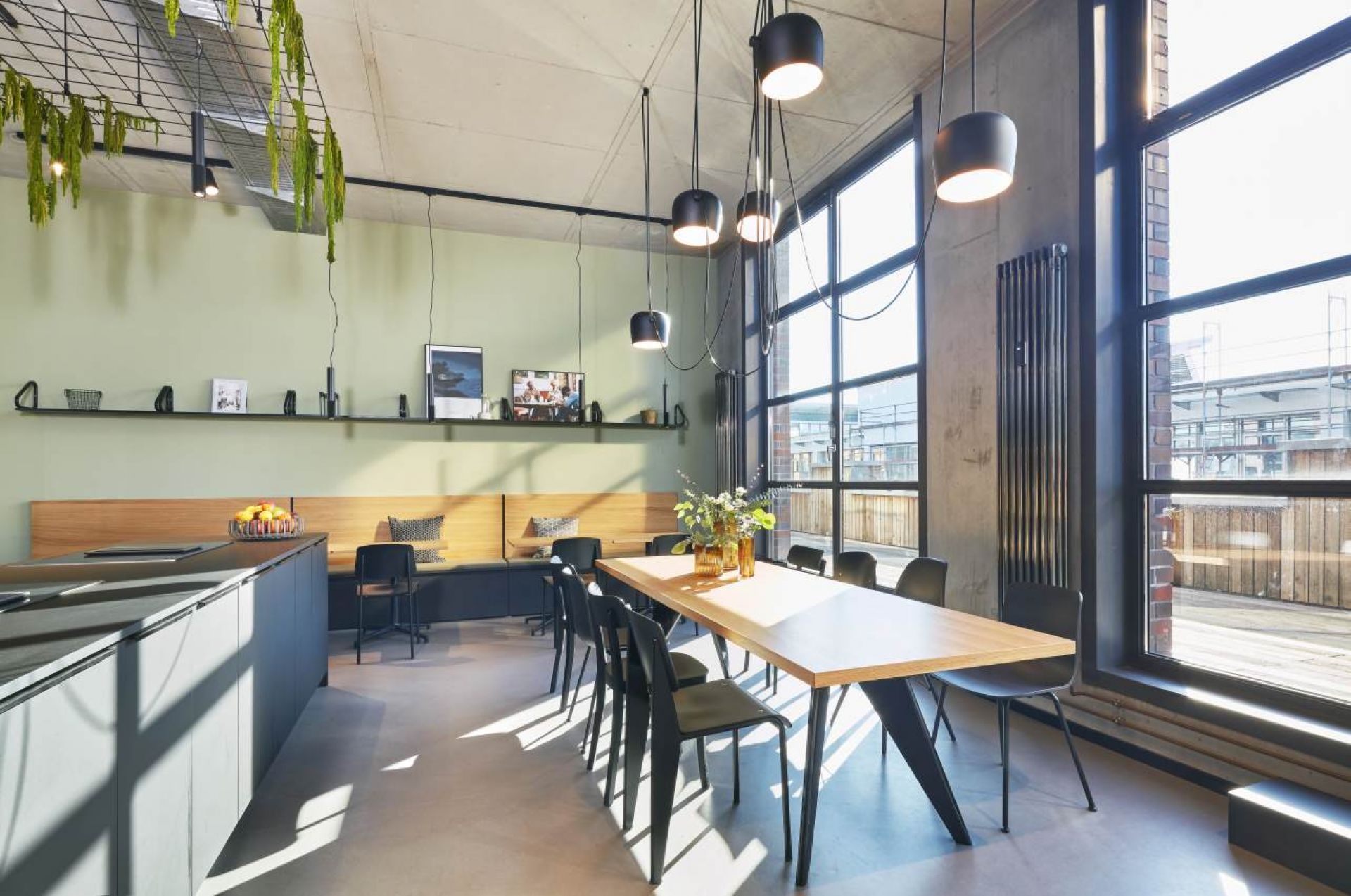 Heller Raum mit Vitra EM Table Holztisch, Stühlen und großen Fenstern. Esszimmer-Möbel.