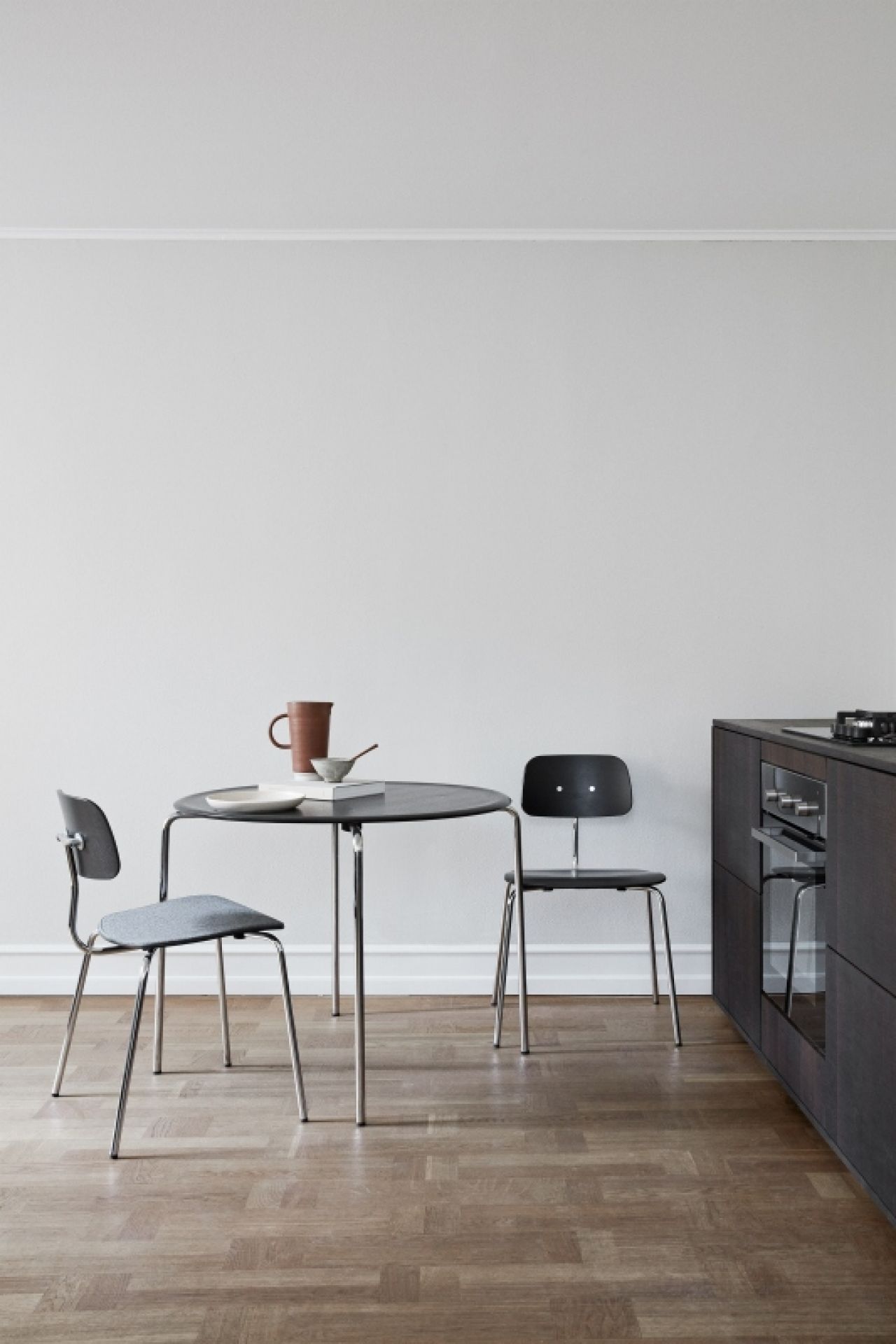 Kevi Stuhl 2060 Montana, grauer und schwarzer Designstuhl mit Stahlgestell an Esstisch in Küche.