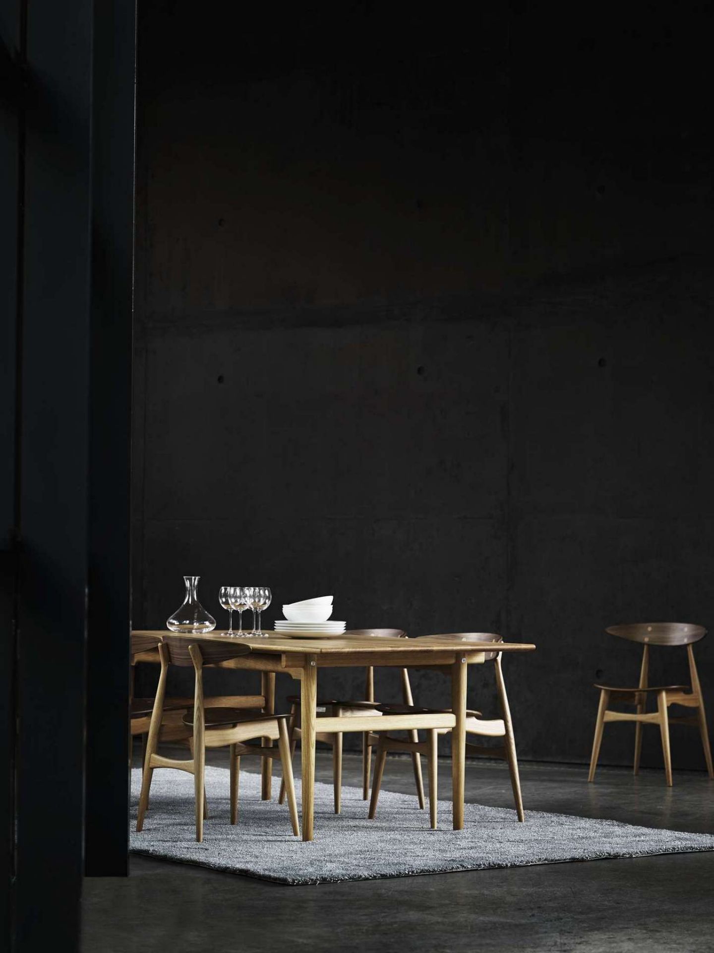 CH327 Tisch von Carl Hansen mit Stühlen, Karaffe, Gläsern und Geschirr auf einem Teppich.