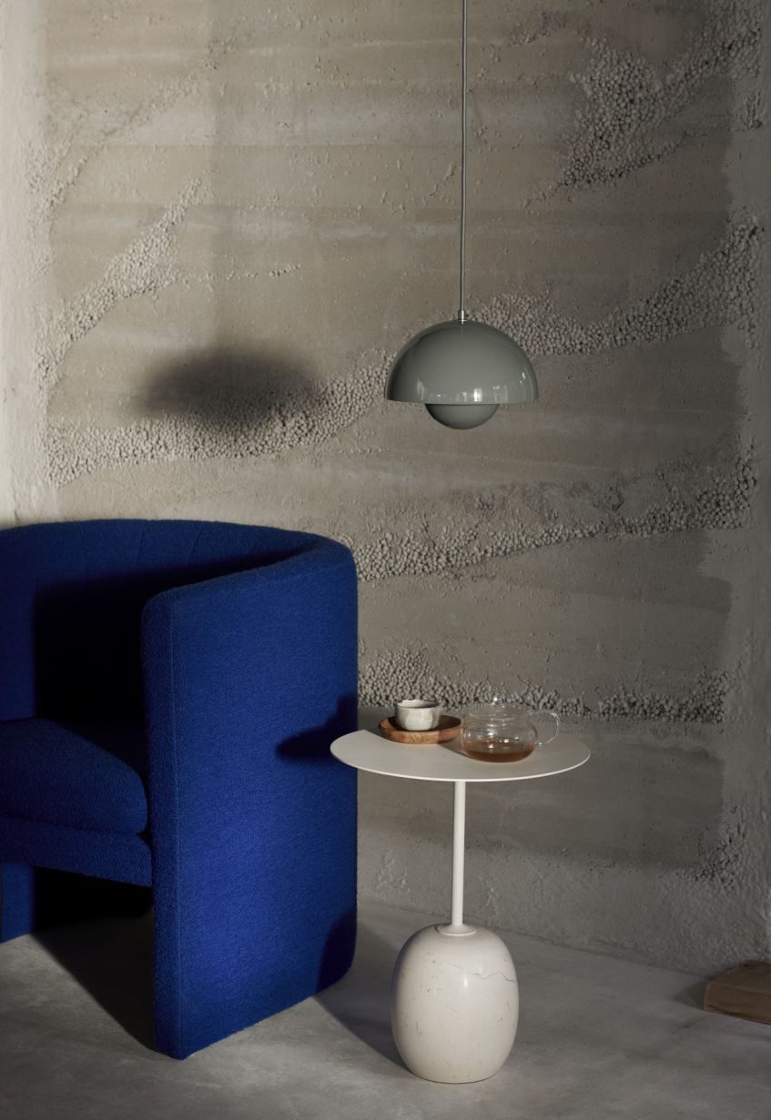 Graue AndTradition Flowerpot VP1 Pendelleuchte über blauem Sessel und Beistelltisch mit Teegeschirr in modernem Interieur.