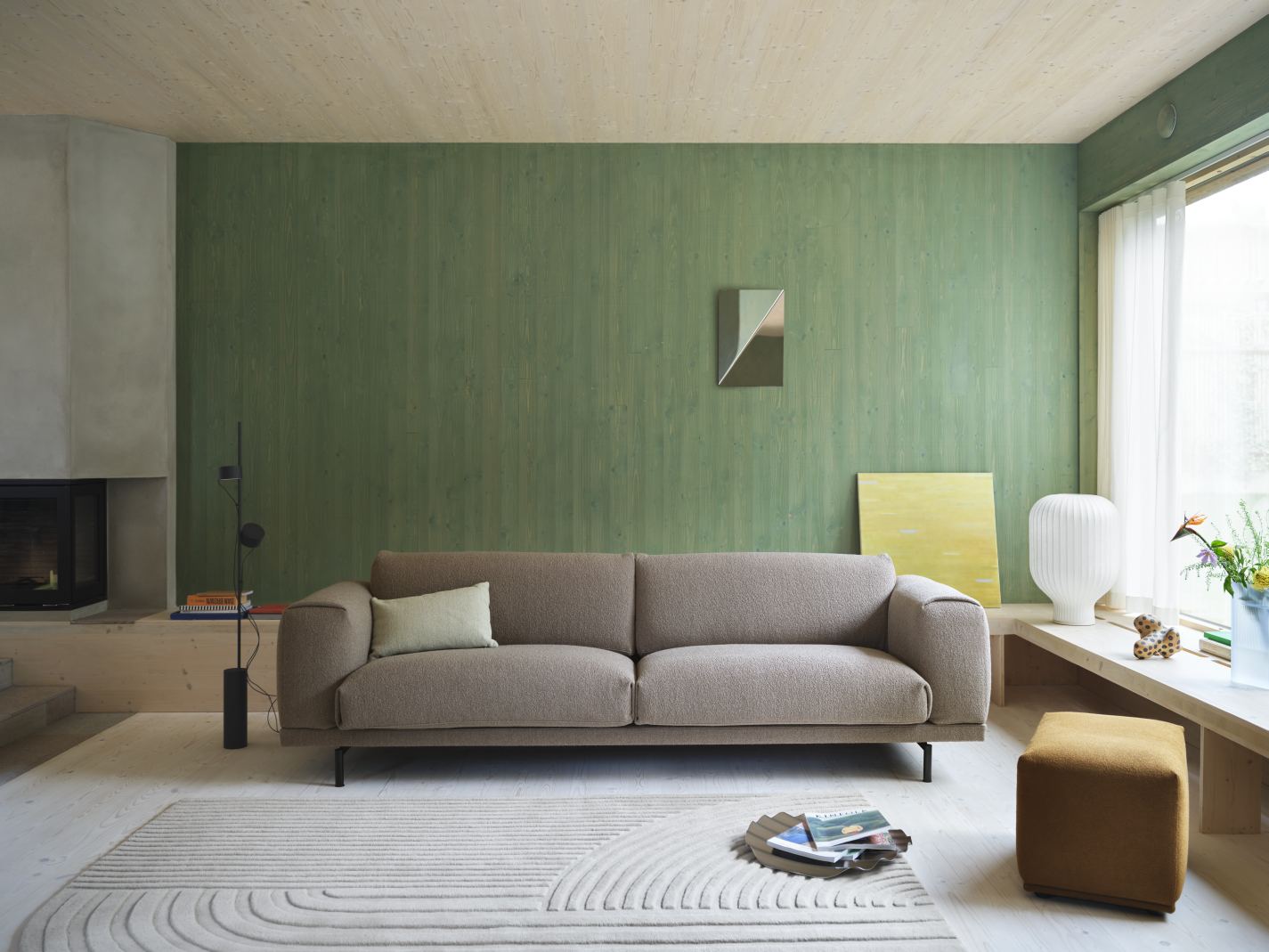 Beige Muuto Rest 2-Sitzer Sofa im Wohnzimmer mit Teppich, Kamin und grüner Wand.