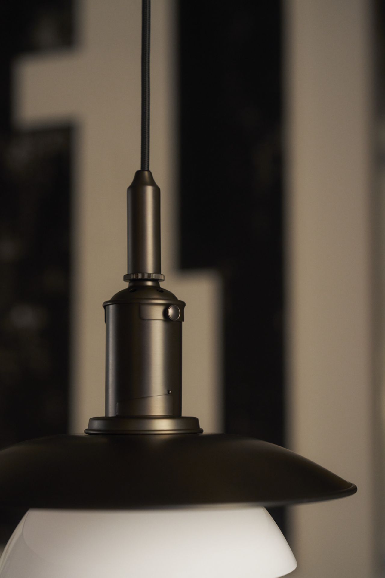 Detailaufnahme der PH 3/3 Pendelleuchte von Louis Poulsen in gealtertem Messing mit Opalglas Schirm.