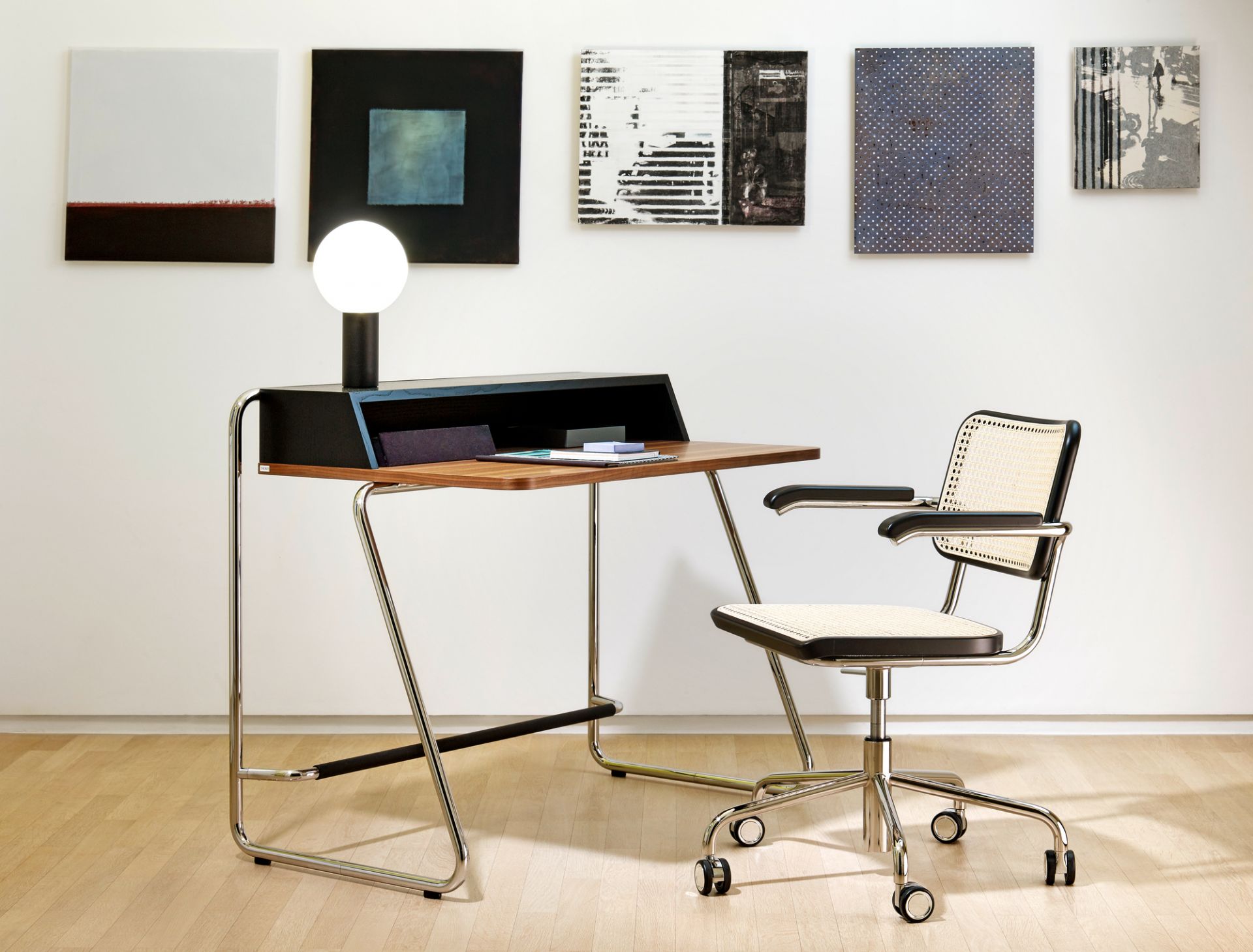 S 1200 Thonet Sekretär mit Stahlrohrgestell und passendem Bürostuhl mit Wiener Geflecht vor Kunstwerken.