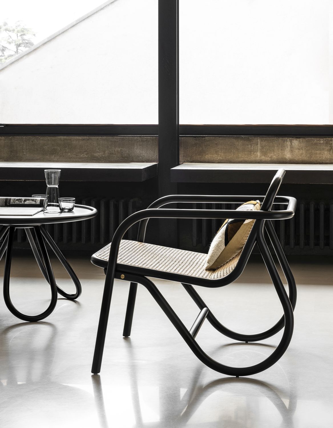 N. 200 Sessel von Wiener GTV Design mit Rohrgeflecht und schwarzem Gestell neben Beistelltisch.