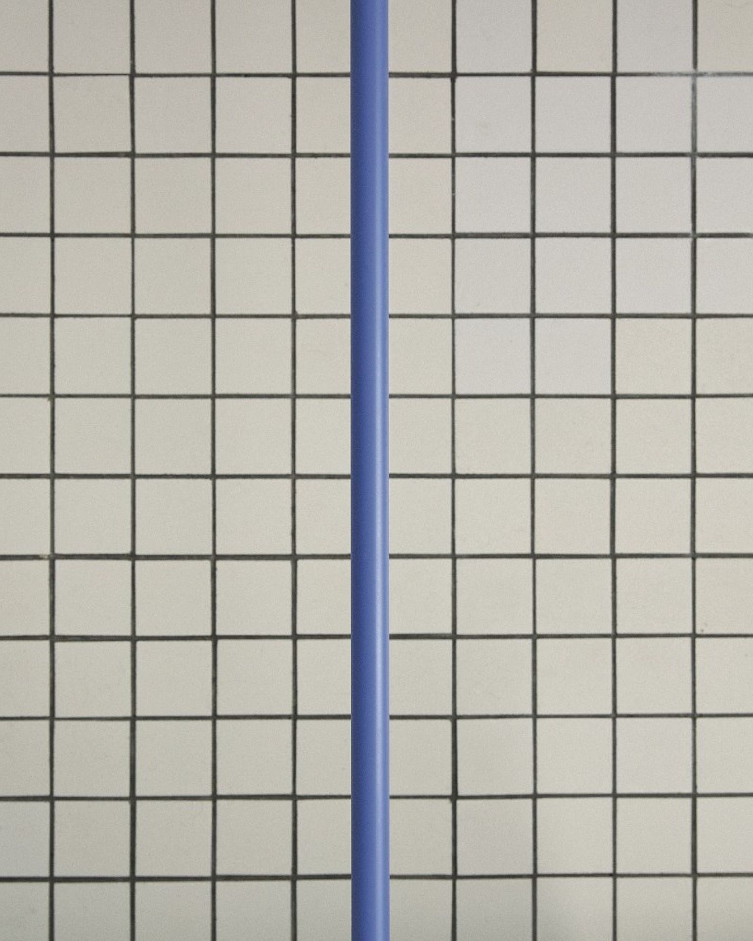 Detailaufnahme der Flos 265 Chromatica Wandleuchte in Blau vor einem quadratischen Fliesenmuster.