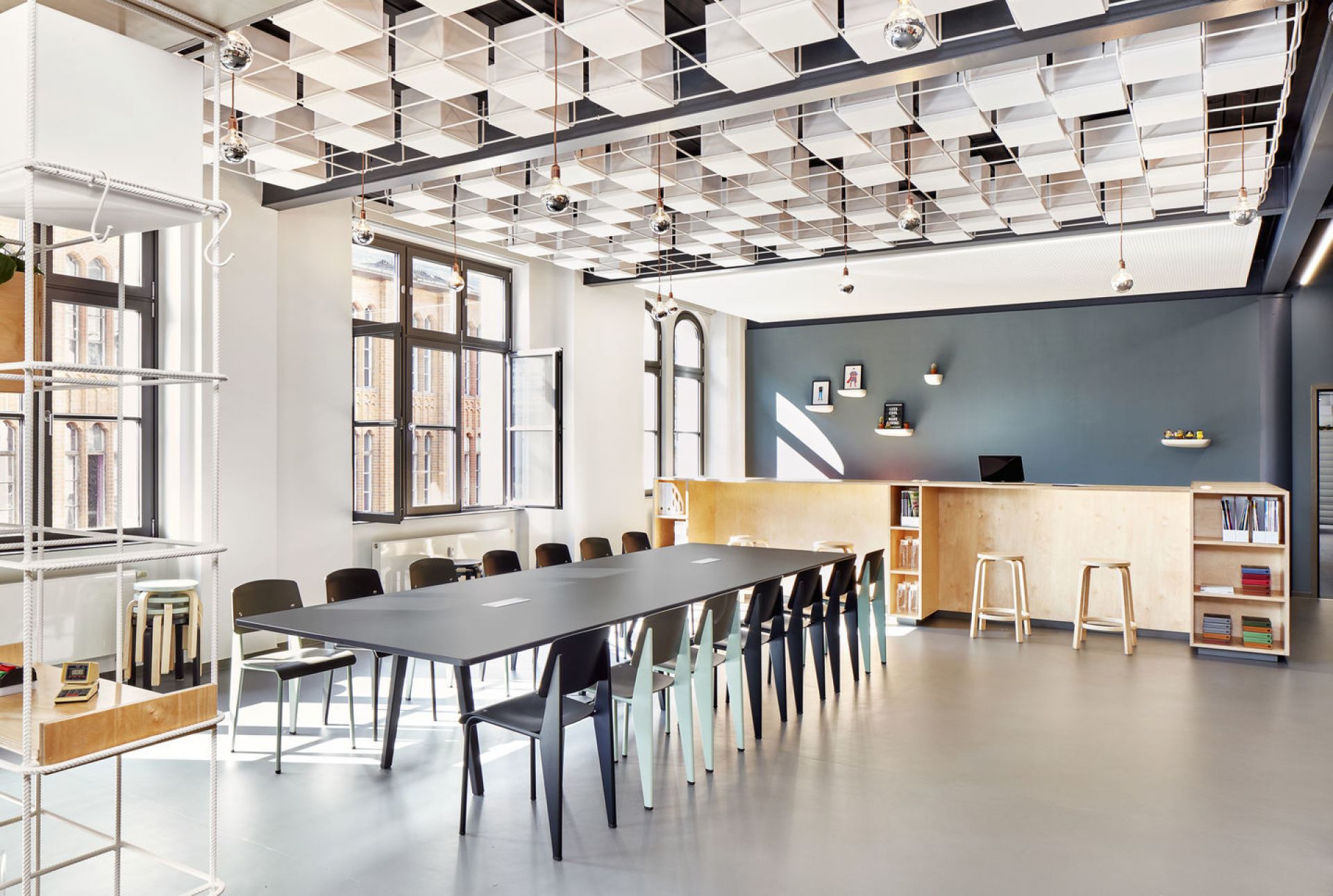 Heller Konferenzraum mit langem Tisch und verschiedenen Vitra Standard Stühlen in Schwarz und Mint.