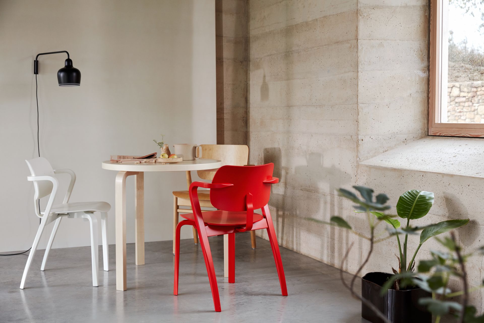 Roter Aslak Chair Stuhl von Artek am Esstisch mit weißen und Holz-Stühlen in modernem Ambiente.
