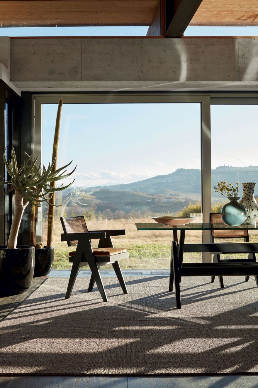Cassina 056 Capitol Complex Table Esstisch mit Glasplatte und Stühlen vor Panoramafenster mit Landschaft.