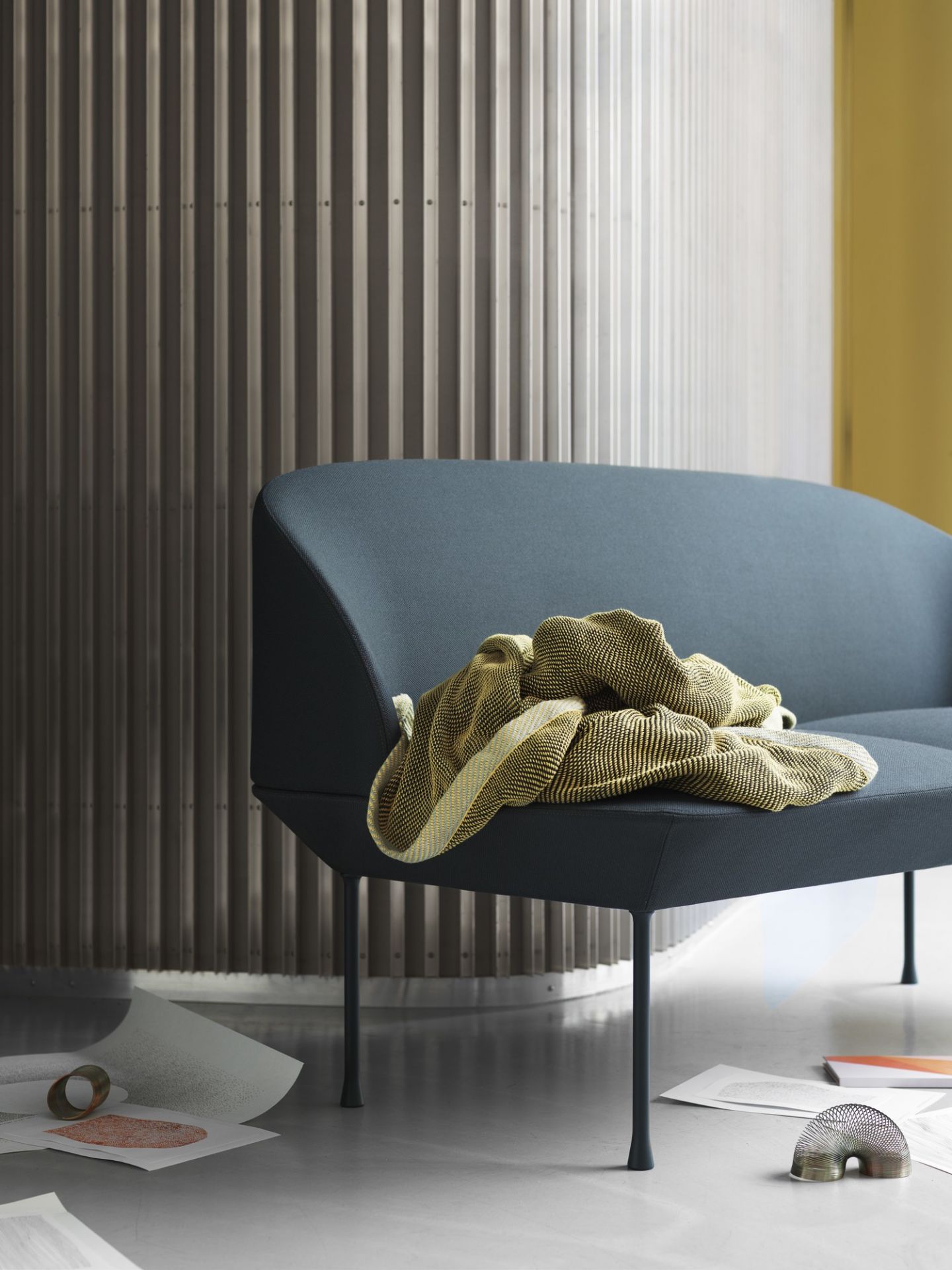 Nahaufnahme des Oslo Sofas von Muuto, ein modernes 2-Sitzer Sofa in blau mit gelber Decke.