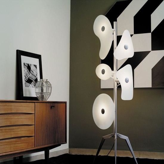 Moderne Stehlampe mit abstrakt geformten, weißen Lampenschirmen und silbernem Stativfuß im stilvollen Wohnzimmer.