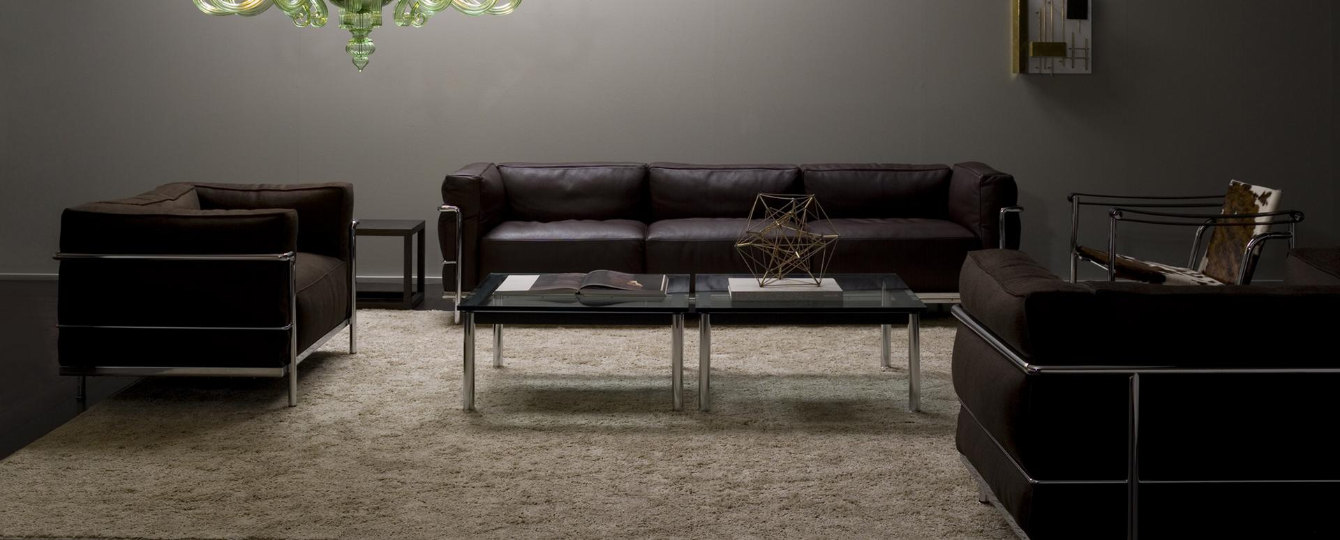 Wohnzimmer mit braunem Ledersofa und zwei Sesseln im Stil des Cassina Grand Confort.