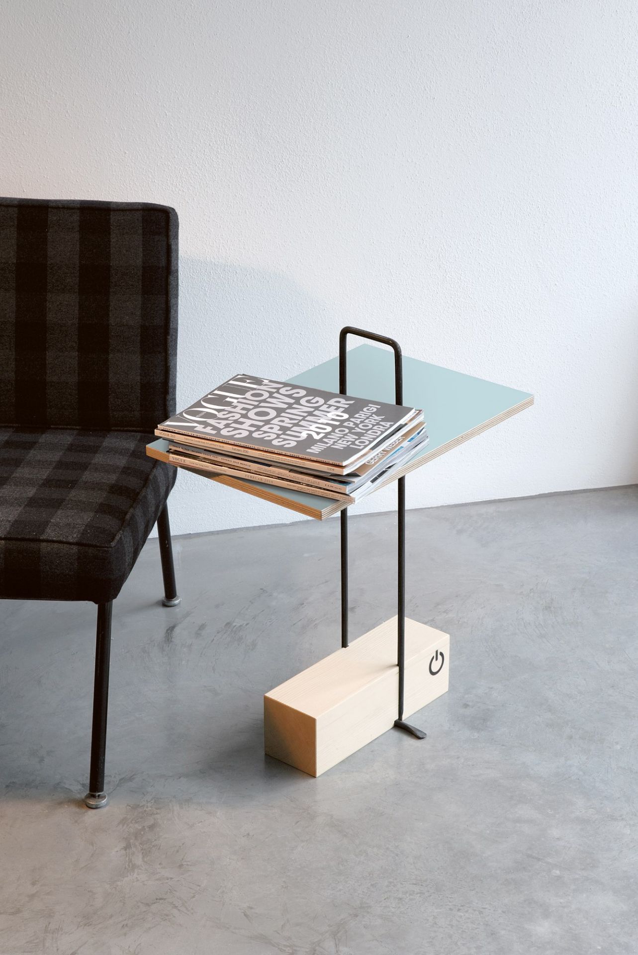 Abgemahnt Beistelltisch von Nils Holger Moormann mit Magazinen neben einem Stuhl im modernen Design.