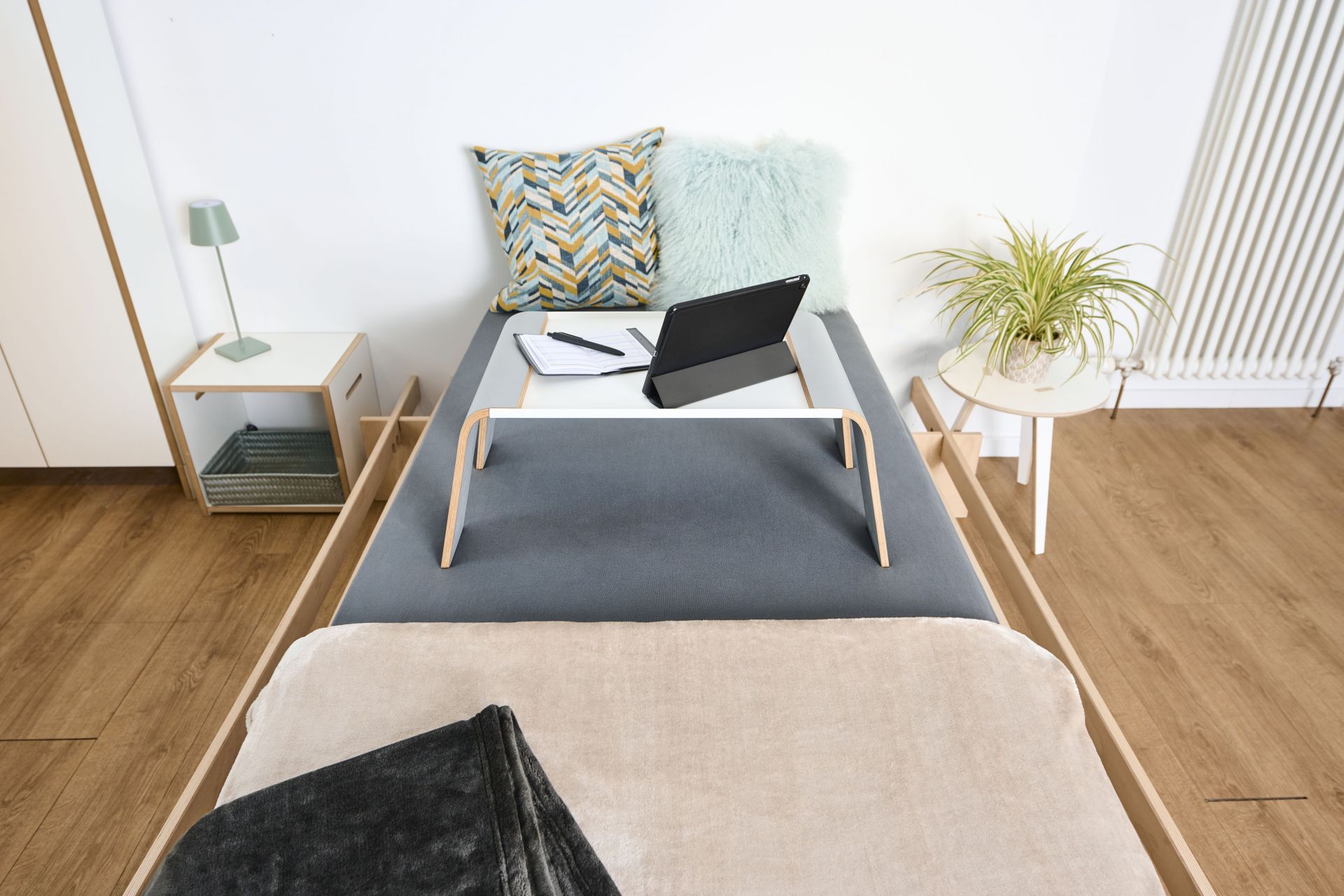 Tojo Notebook-Tablett auf Bett mit Tablet, Notizbuch und Stift für entspanntes Arbeiten im Schlafzimmer.