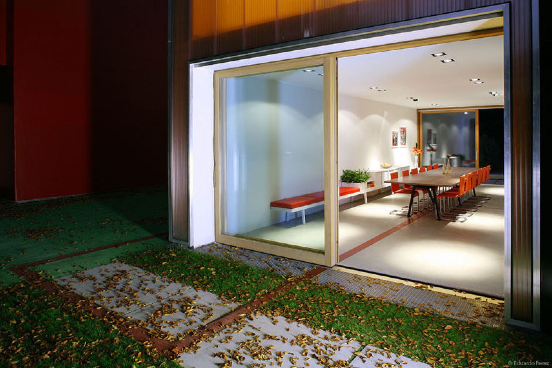 Innenaufnahme eines modernen Esszimmers mit Vitra .05 Stühlen in Orange um einen langen Holztisch.