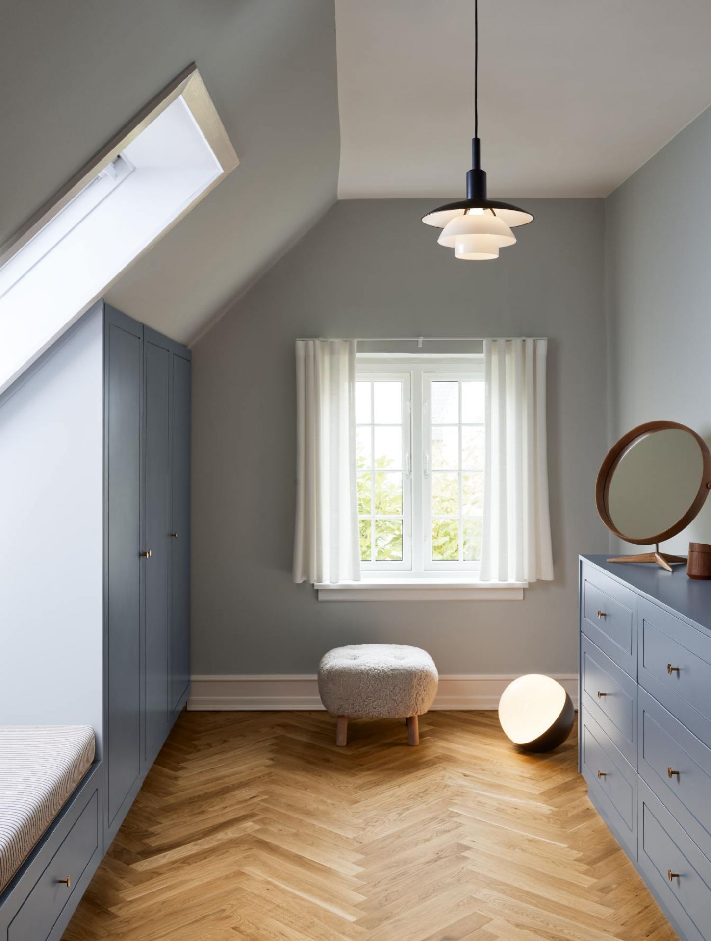Helle, moderne Dachgeschoss-Einrichtung mit PH Pendelleuchte von Louis Poulsen und blauen Möbeln.