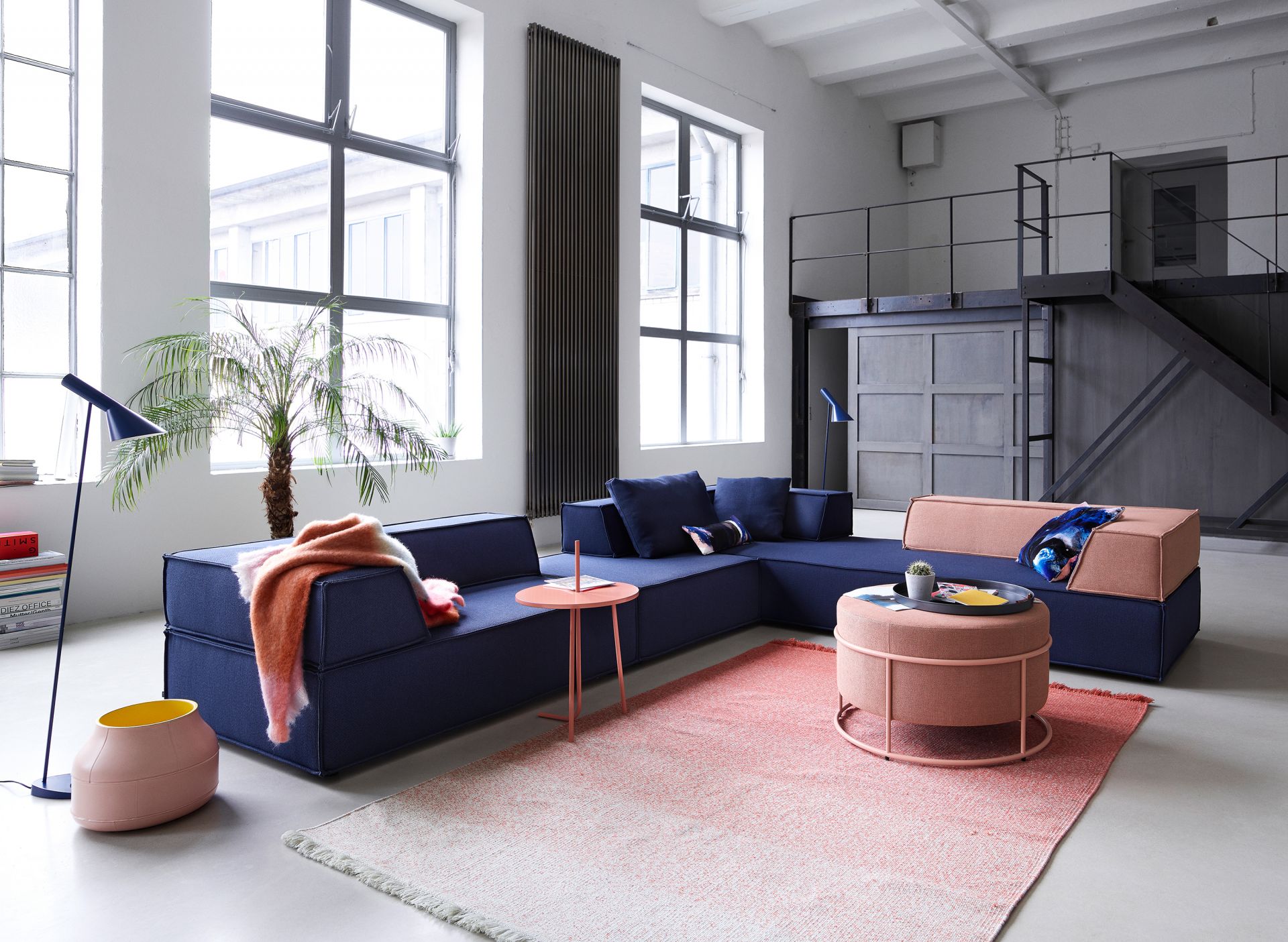 Modernes Trio Sofa Eckkombination in Blau und Rosa mit Beistelltisch und Teppich in Loft-Atmosphäre.