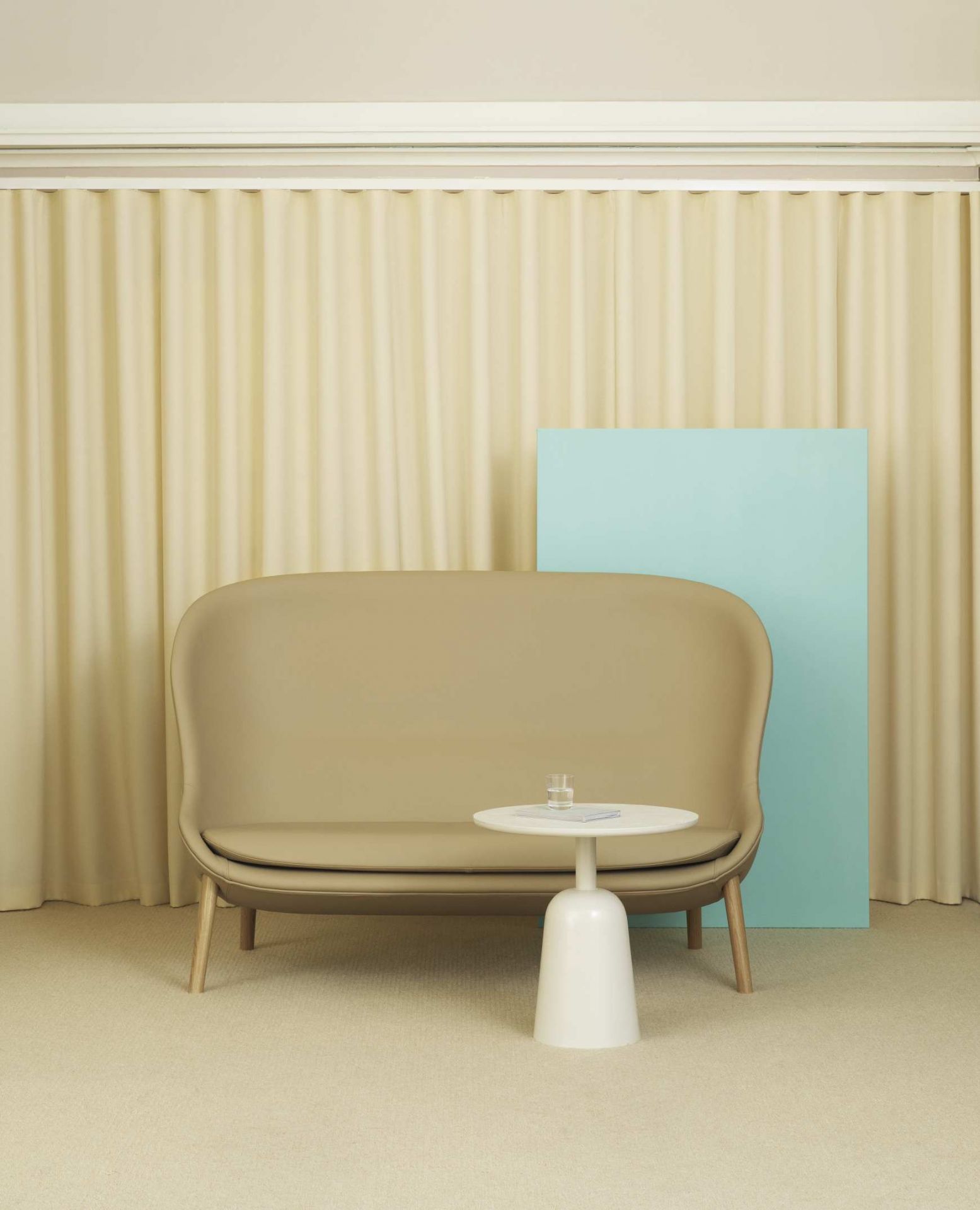 Normann Copenhagen Turn Table Beistelltisch aus Marmor, weiß, mit Sofa und Wasserglas.