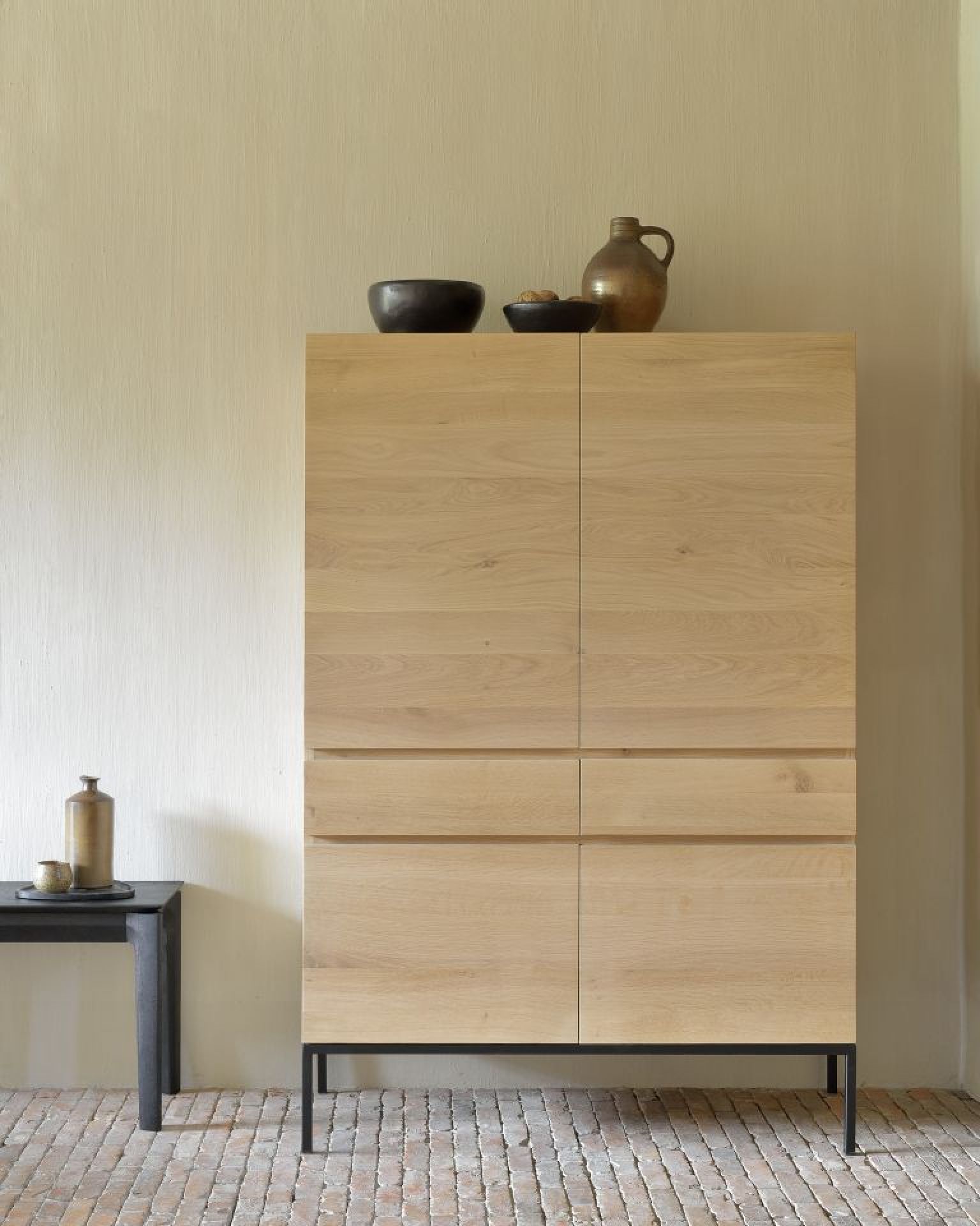 Ligna Hochschrank Eiche Ethnicraft: Moderner Holzschrank mit Schubladen und Deko-Elementen im Wohnraum.
