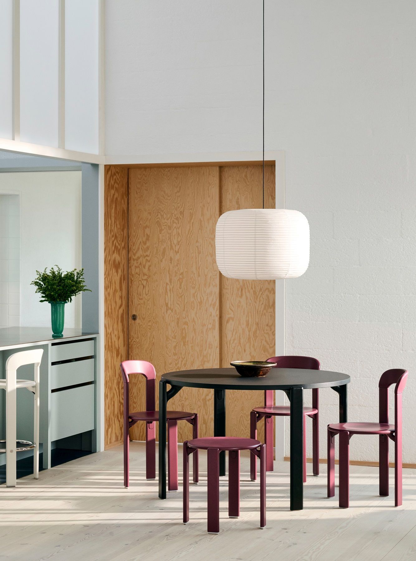Esszimmer mit schwarzem Tisch, lila Stühlen und einem Rey Stool Hocker von Hay.