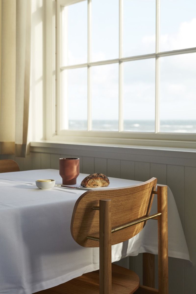 Vester Chair Stuhl von Skagerak by Fritz Hansen am Esstisch mit Meerblick.