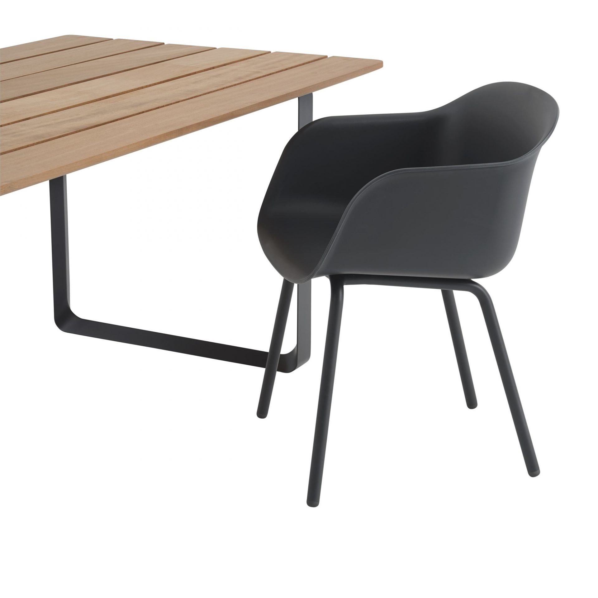Muuto Fiber Outdoor Armchair: Schwarzer Armlehnstuhl aus Kunststoff mit filigranem Metallgestell am Holztisch.