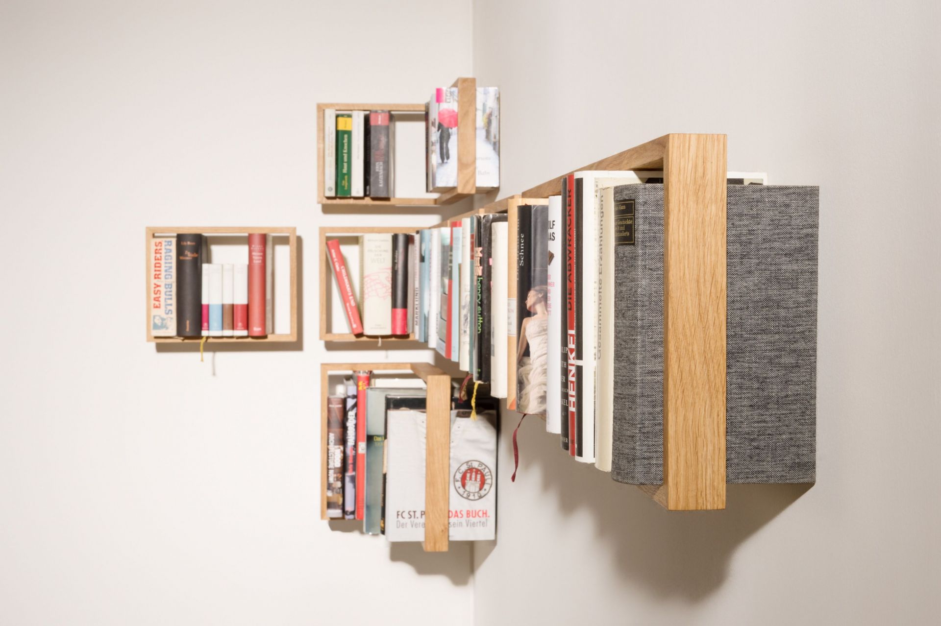 Detailaufnahme des Regal b Eiche das kleine b EINZELSTÜCK, ein modernes Bücherregal aus hellem Holz an einer weißen Wand.