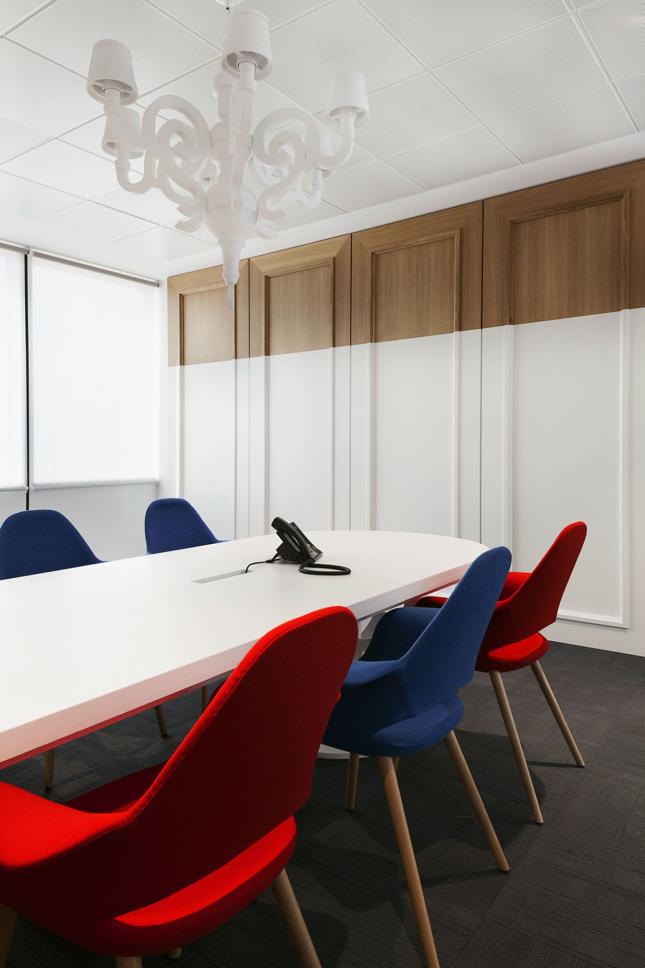 Konferenzraum mit Organic Conference Stühlen von Vitra in Rot und Blau um einen Tisch.