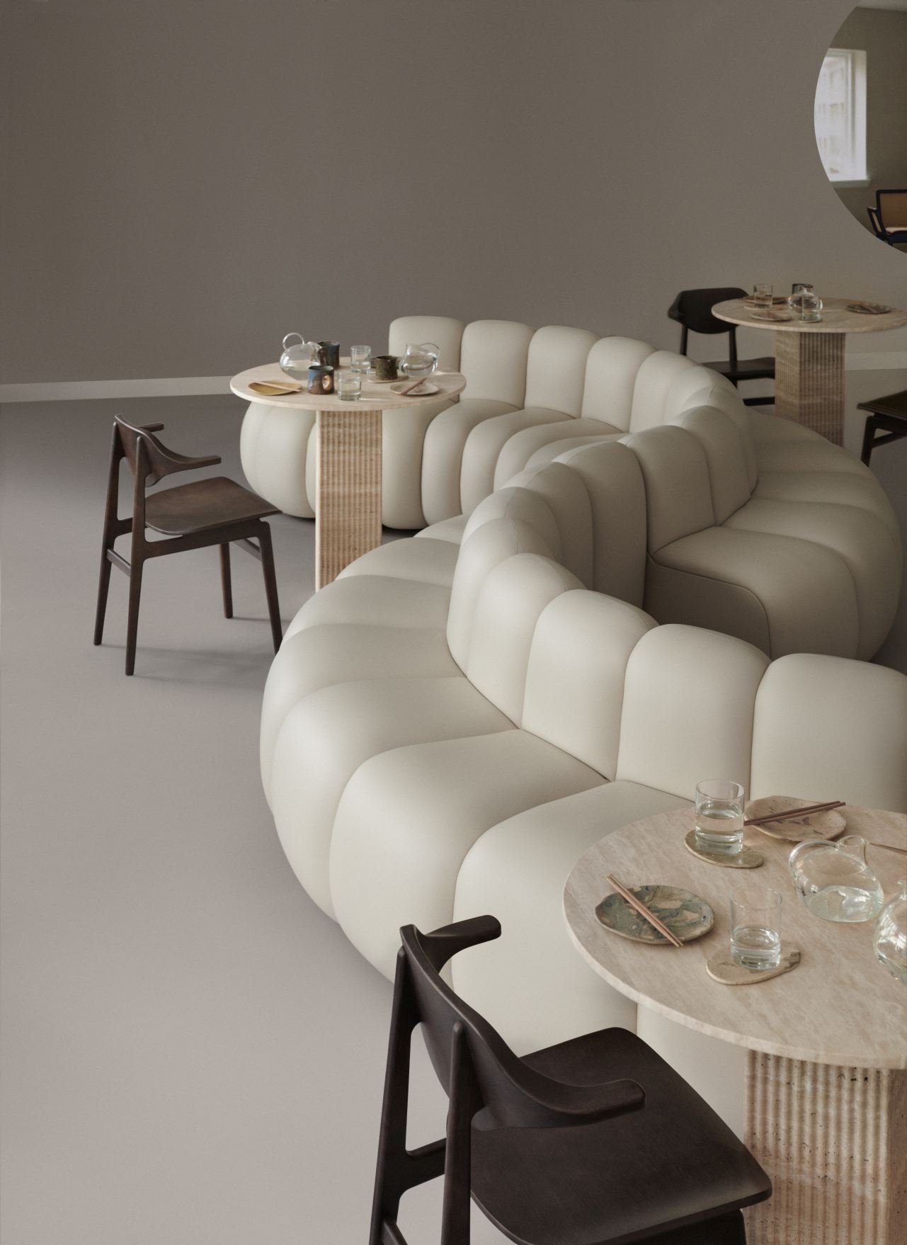 NORR11 Bufala Dining Chair aus dunklem Holz an Esstisch mit geschwungenem Sofa im Restaurant.