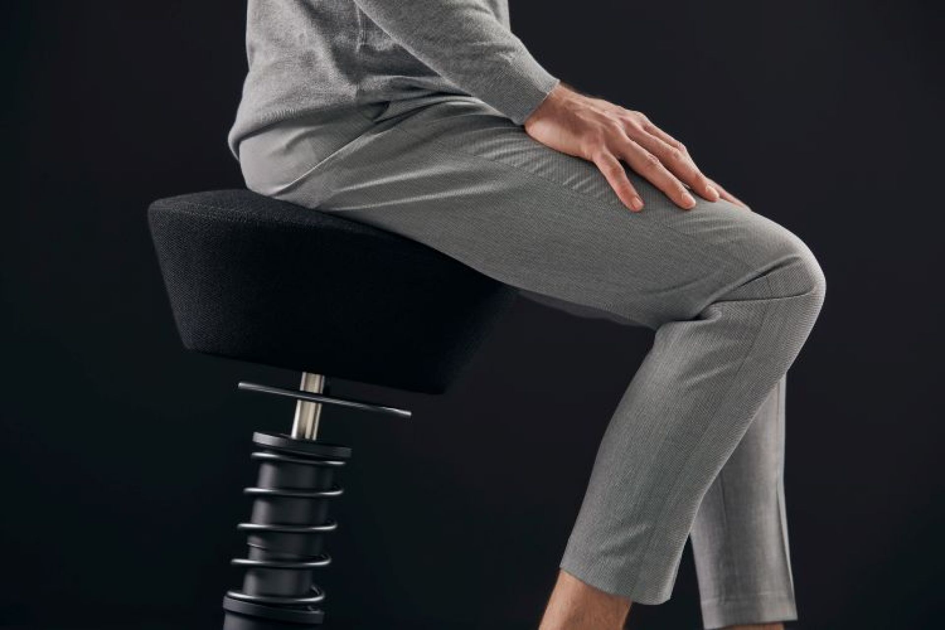 Mann sitzt auf einem schwarzen Swopper Hocker mit Rollen, ergonomischer Bürostuhl für aktives Sitzen.