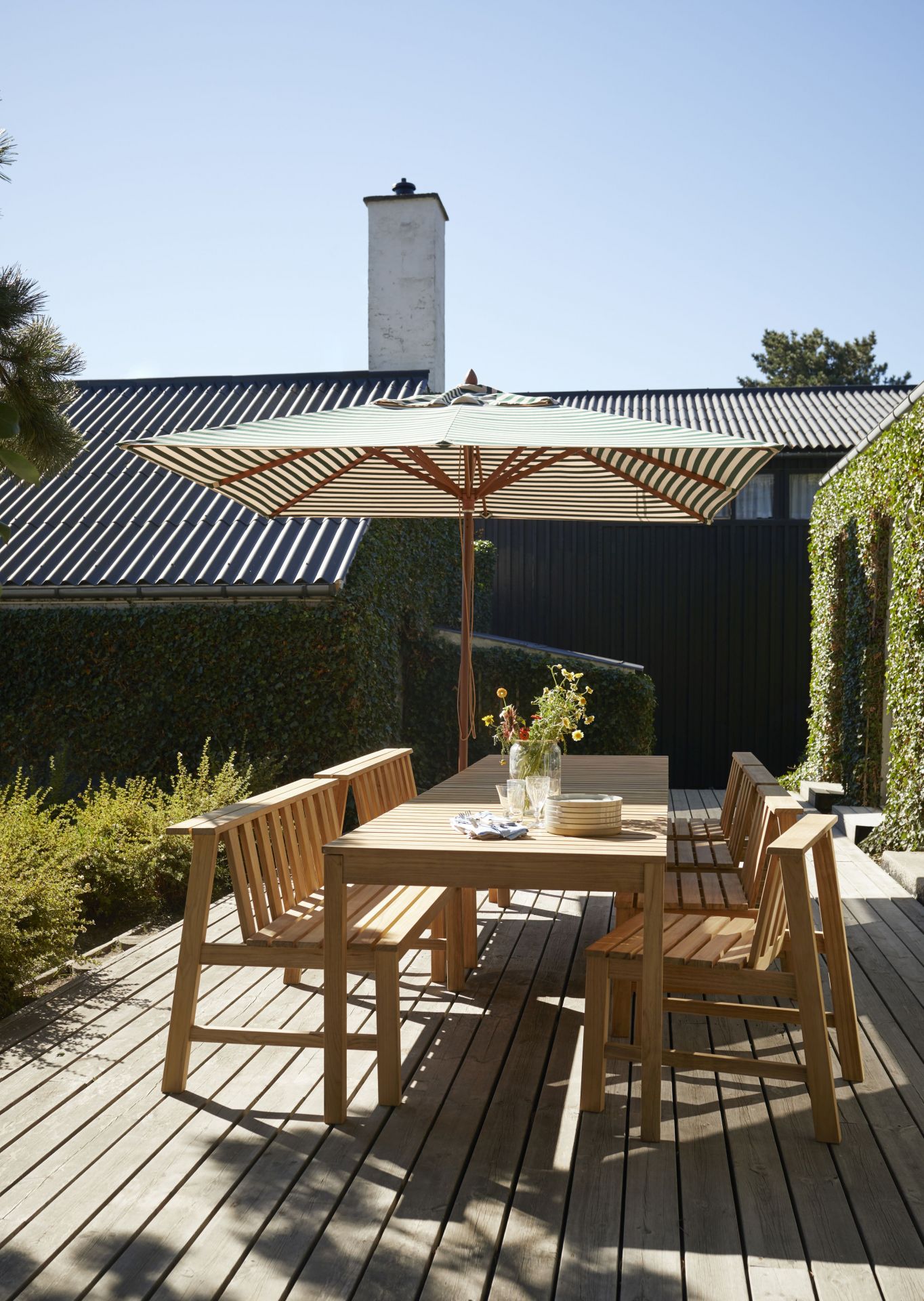 Cadence Bank Teak Gartengarnitur von Skagerak by Fritz Hansen mit Tisch, Stühlen und Sonnenschirm.