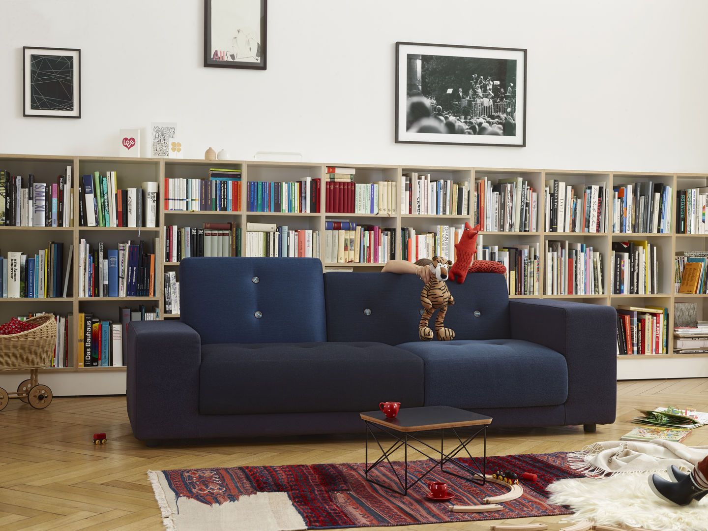 Blaues Vitra Polder Sofa in einem Wohnzimmer mit Bücherregal und Spielzeug.