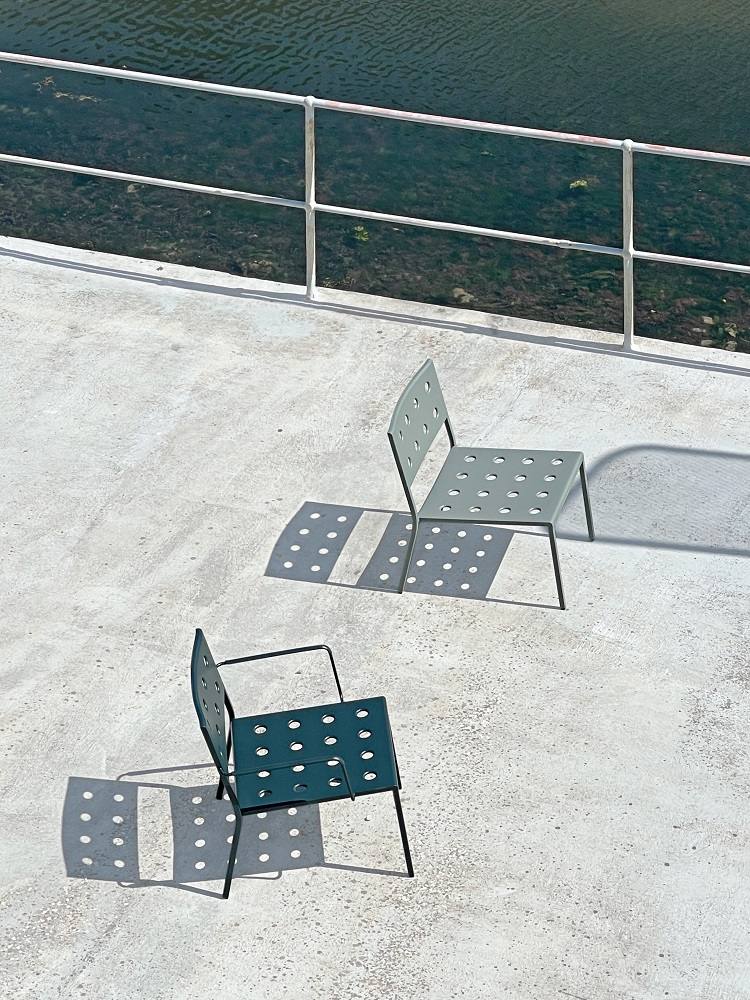 Zwei Hay Balcony Outdoor Lounge Chairs in Grün und Grau auf einer Terrasse mit Geländer.